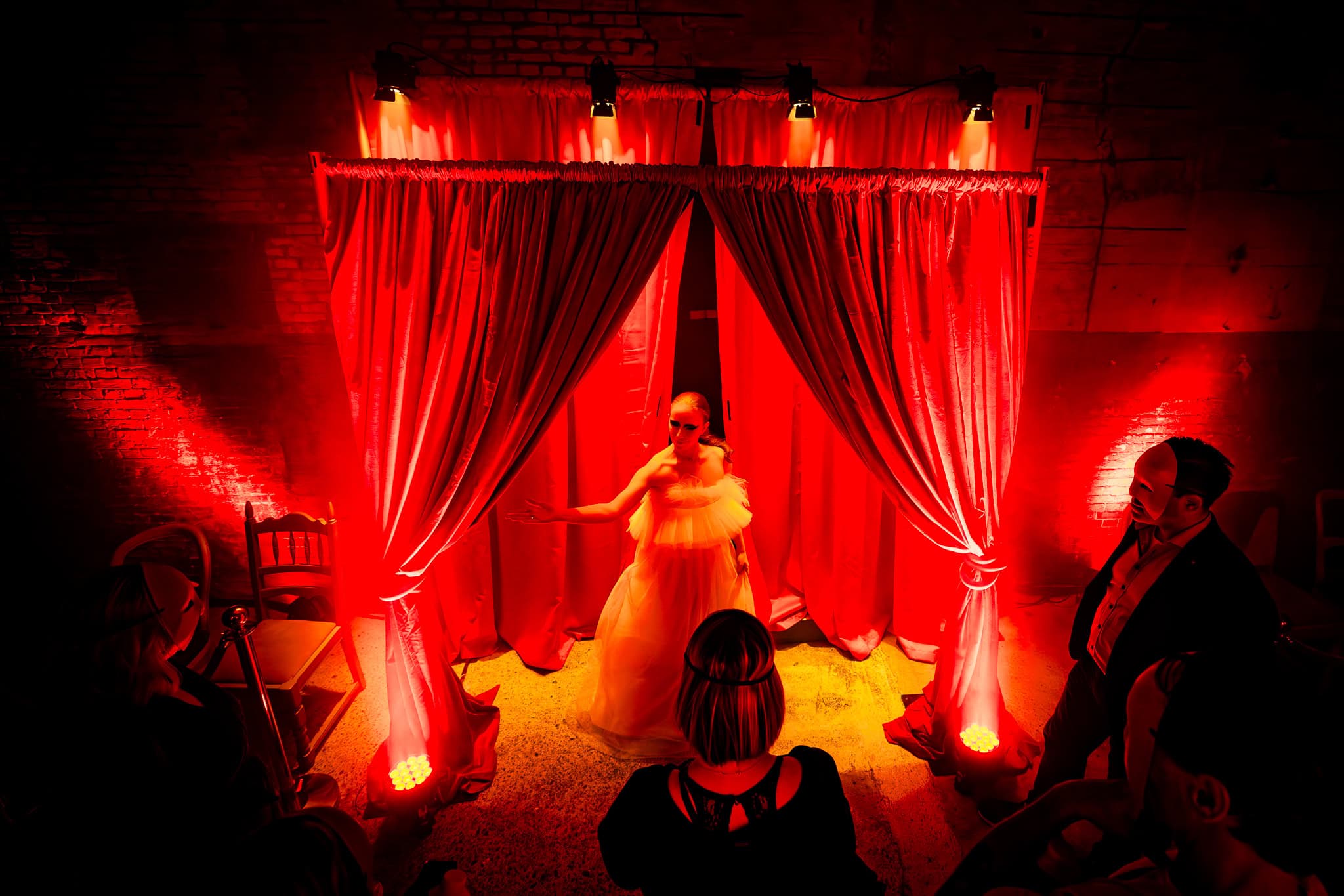 Vrouw presenteert op podium met rode gordijnen en sfeervolle verlichting.