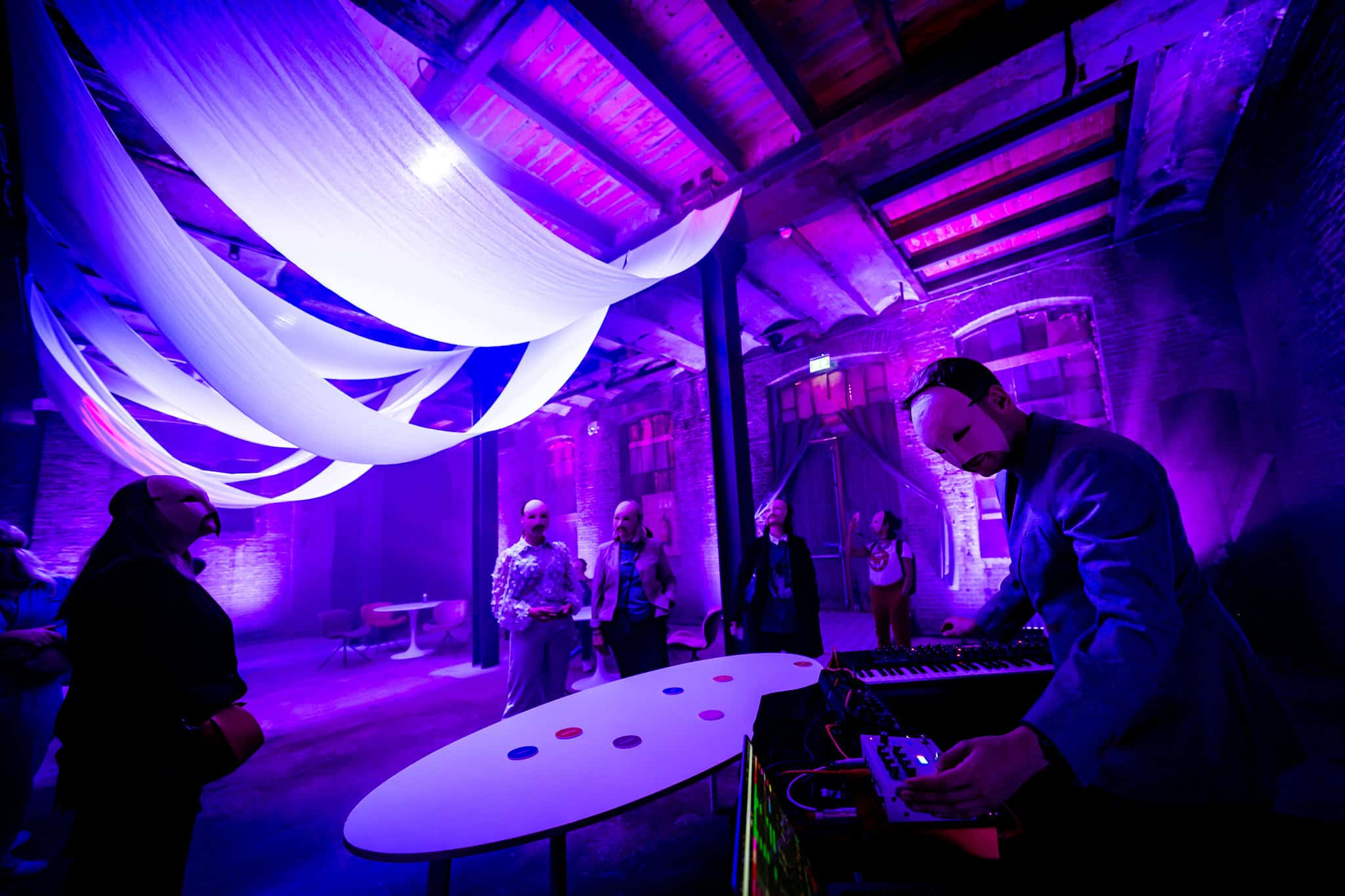 Mensen genieten van muziek en sfeer tijdens een evenement in een sfeervolle, met blauwe en paarse ve.