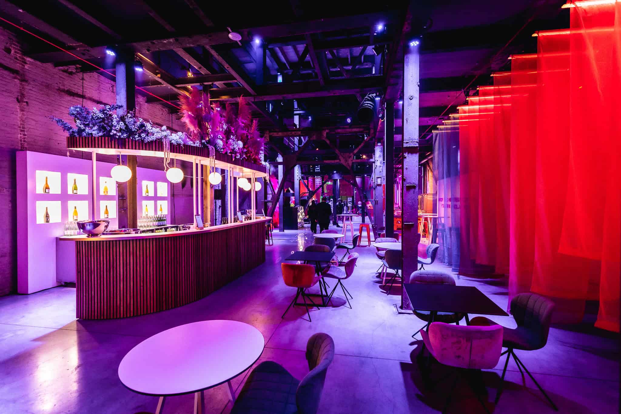 Gezellige lounge met kleurrijk verlichte bar en comfortabele zitplaatsen.