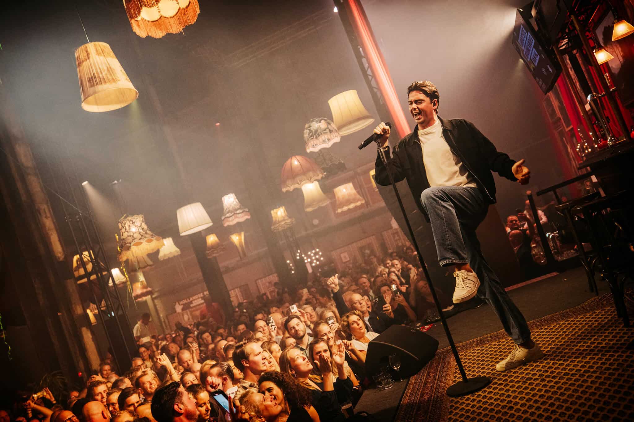 Kunstzinnig podium met zanger en enthousiast publiek tijdens live optreden.