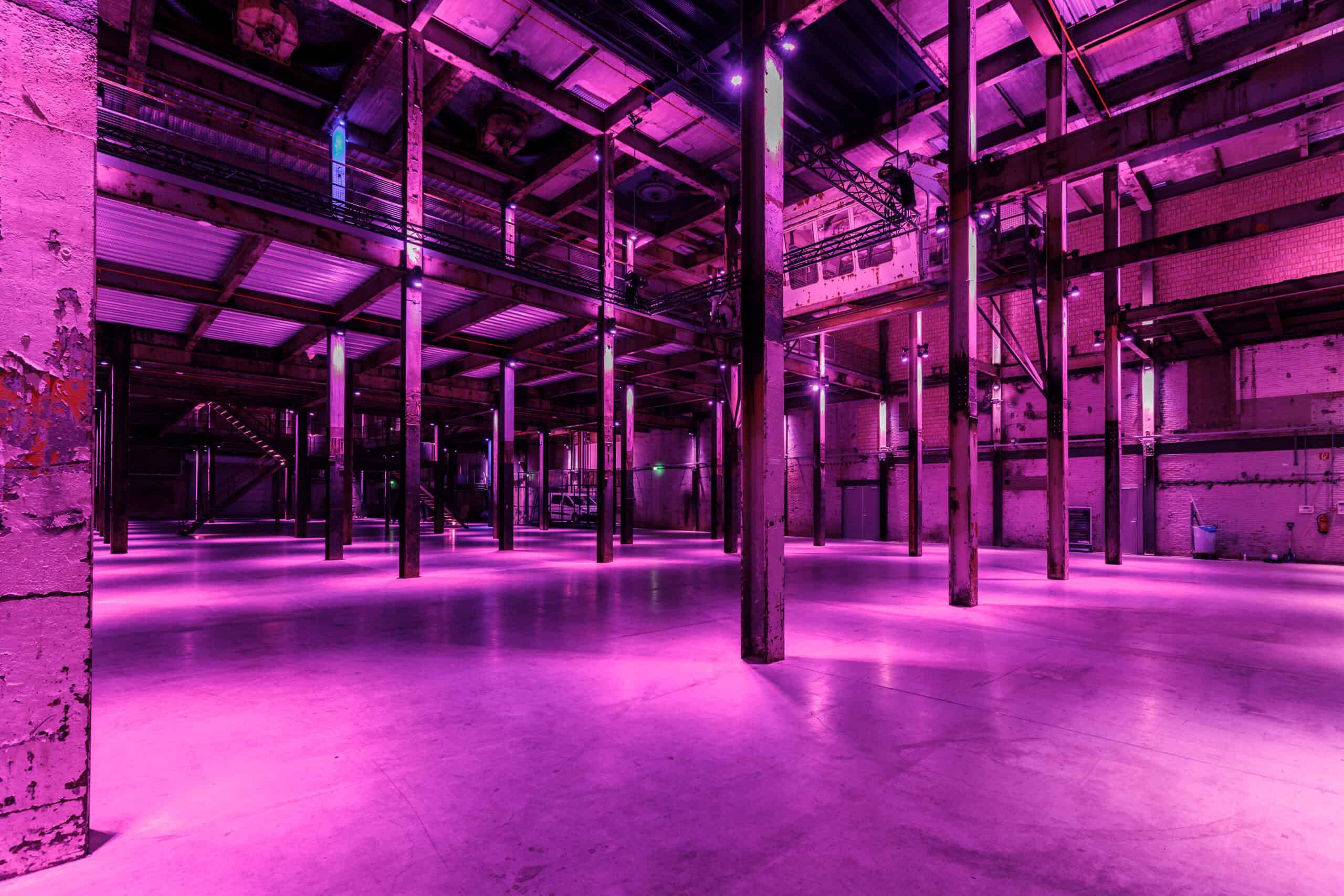 Interieur van de Middenfabriek met levendige roze en paarse verlichting en industriële structuur.