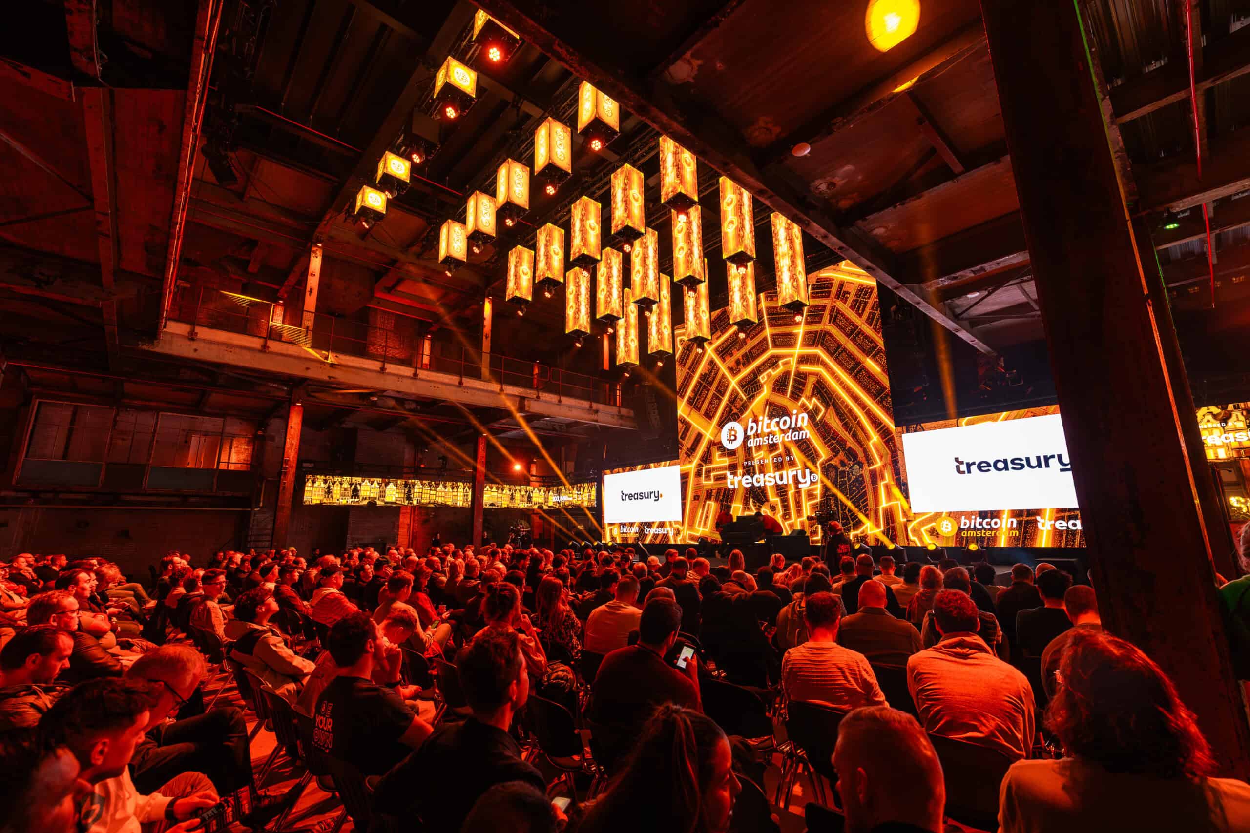 Grootschalig evenement in de Middenfabriek met veel publiek en digitale schermen.