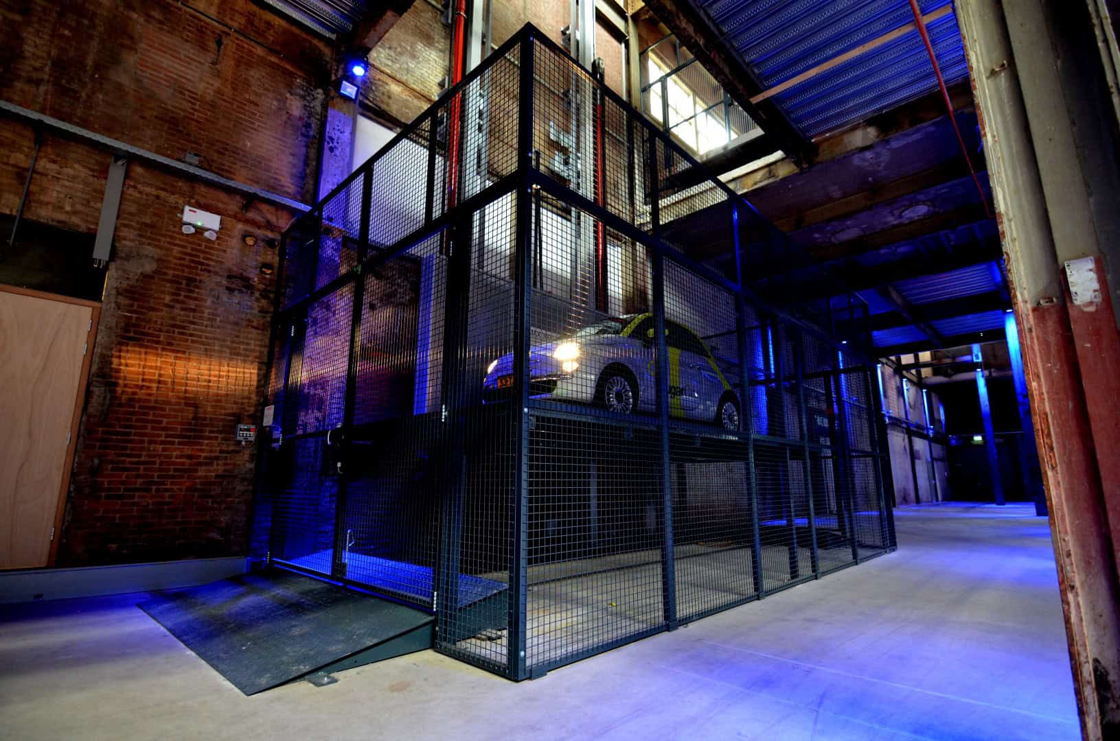 Industriële car lift in de Middenfabriek met metalen structuur en auto.