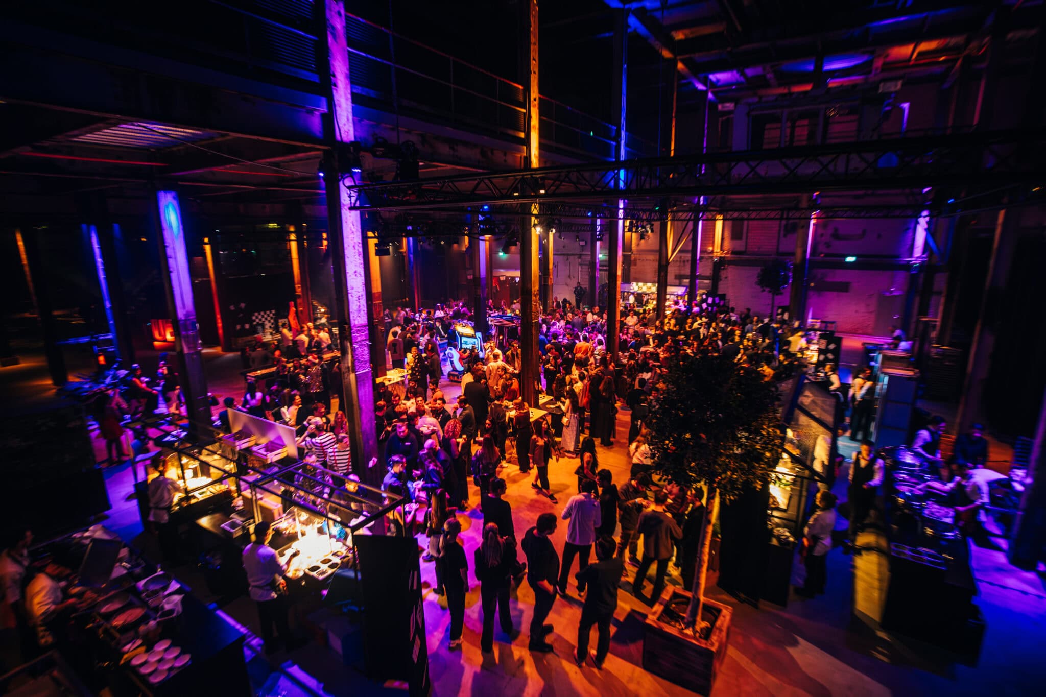 Gezellig drukke scene in de Middenfabriek met bezoekers en verlichte stands.