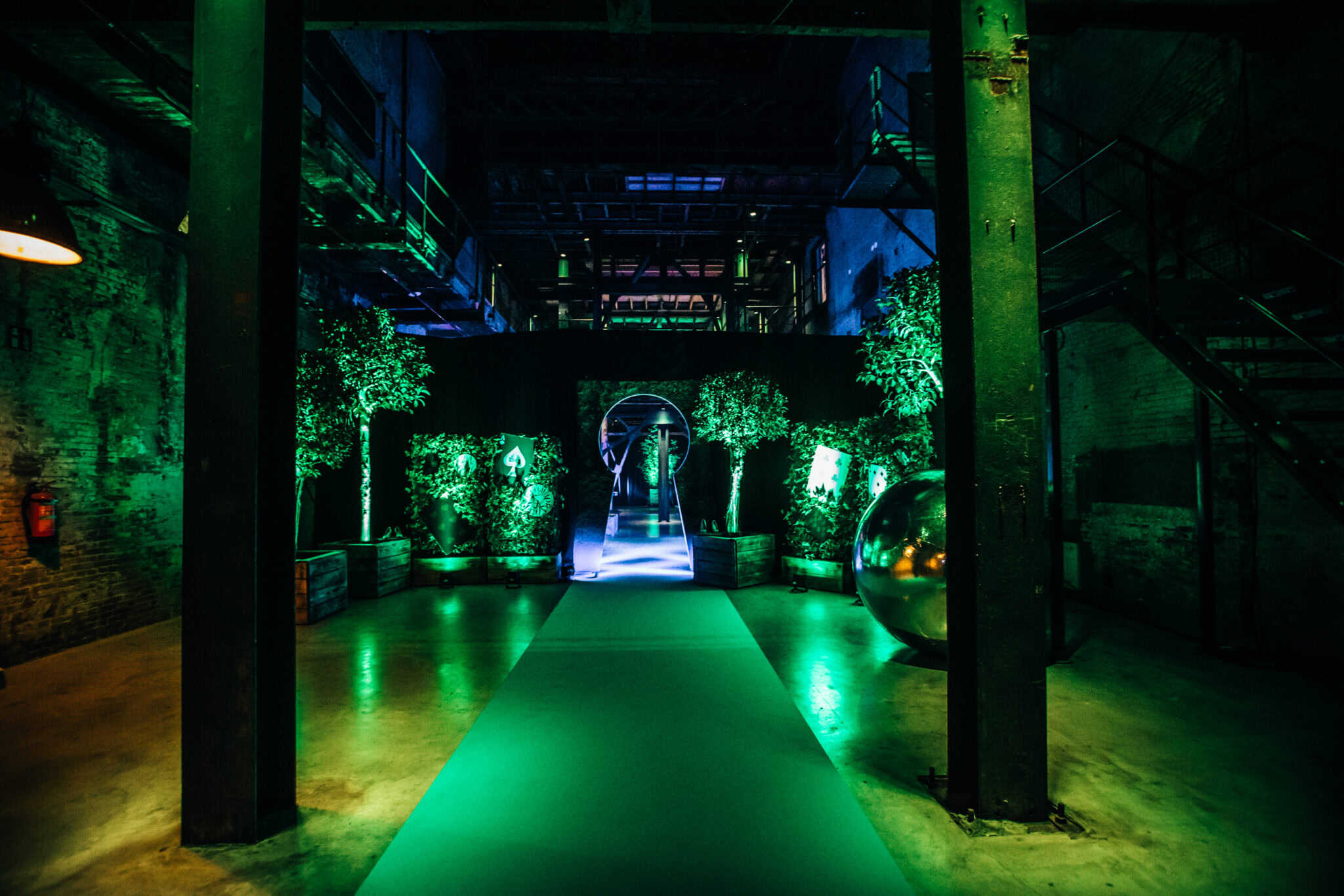 Industriële binnenstraat met groene verlichting en decoratieve planten.