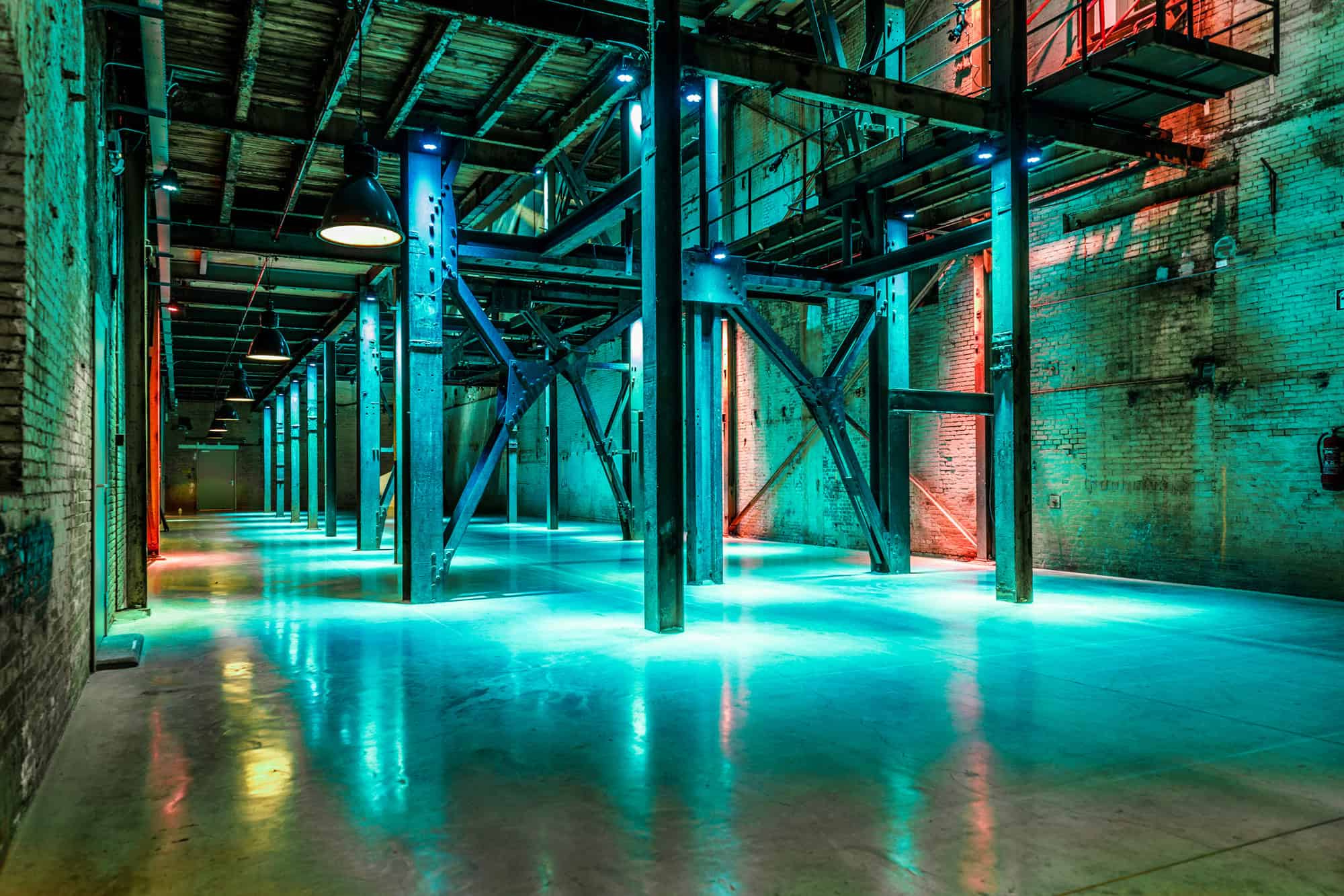 Industrieel interieur met stalen constructies en kleurrijk verlichte vloer.