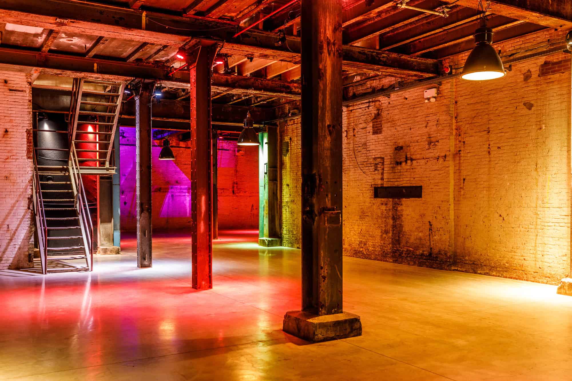 Binnenstraat met industriële uitstraling en kleurrijk verlichte muren.