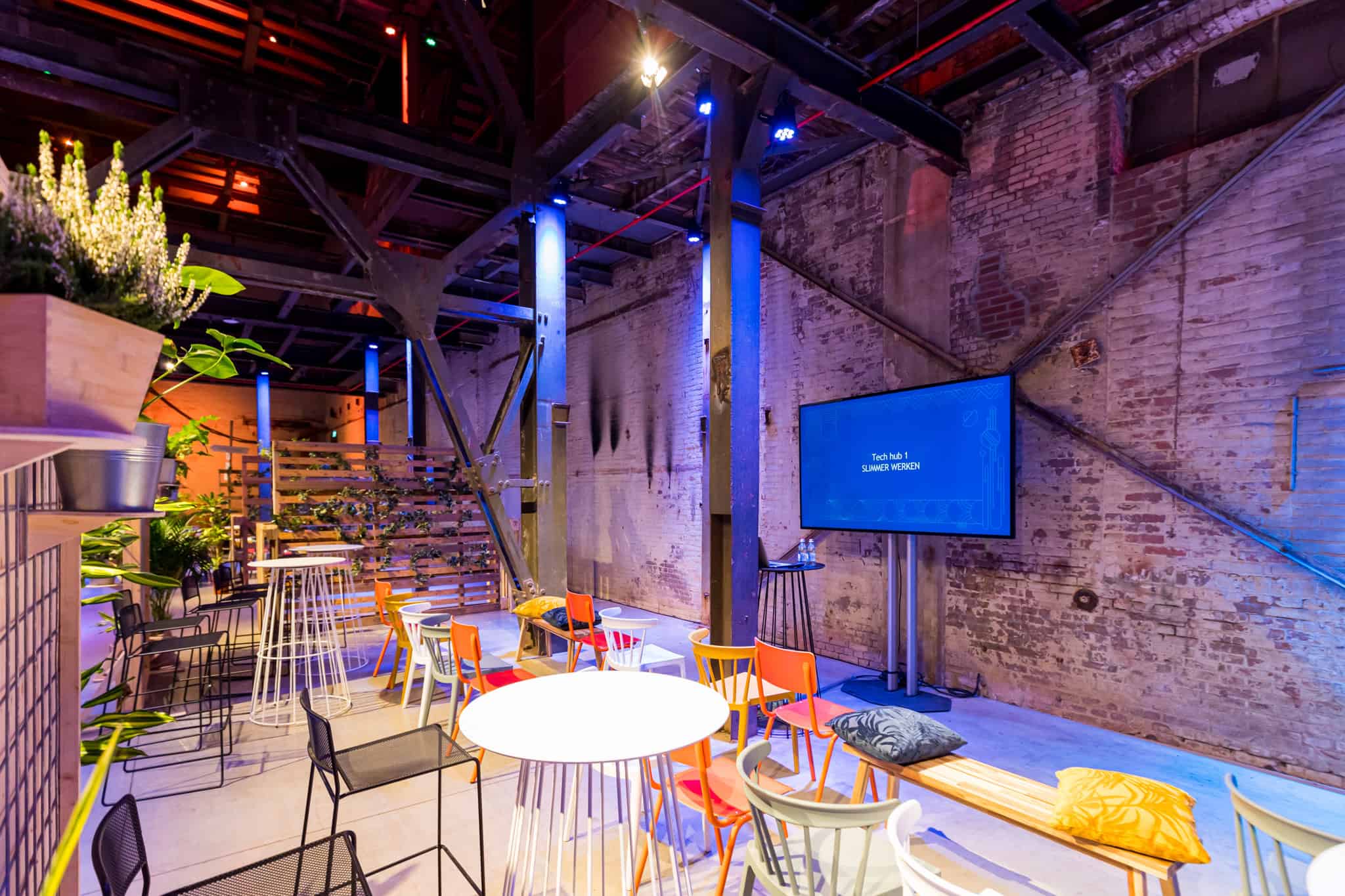 Gezellige binnenruimte met kleurrijke stoelen en industrieel design bij SugarFactory.