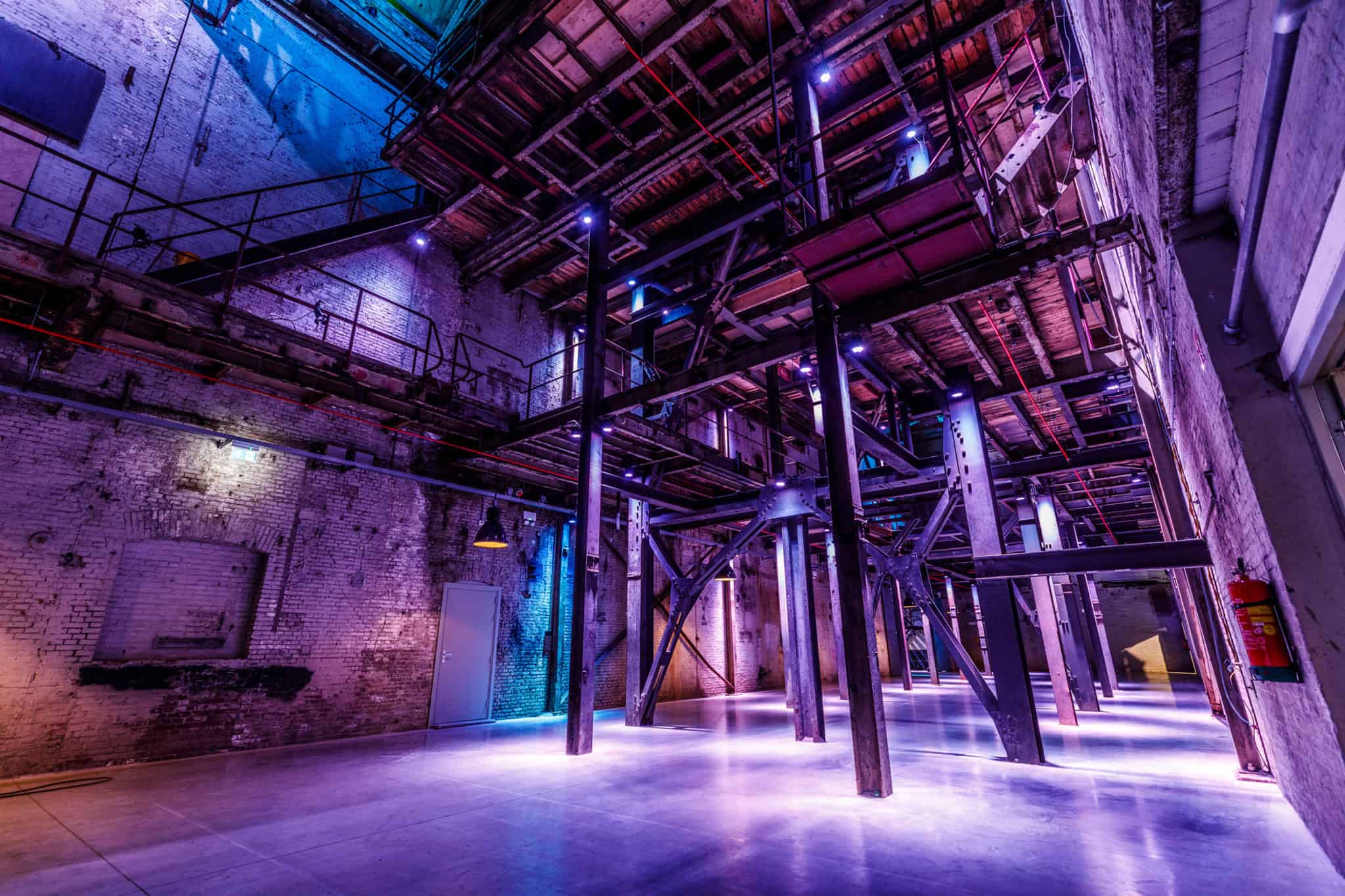 Industrieel interieur met metalen structuren en kleurrijk licht in de binnenstraat.