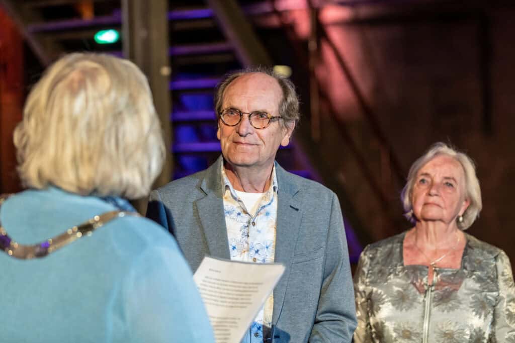 Medewerker ontvangt lintje tijdens ceremonie bij SugarCity, ter ere van zijn jarenlange inzet en bij.