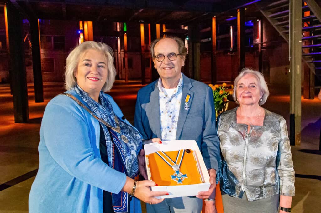 Oud-medewerker ontvangt lintje bij SugarCity tijdens feestelijke gebeurtenis.