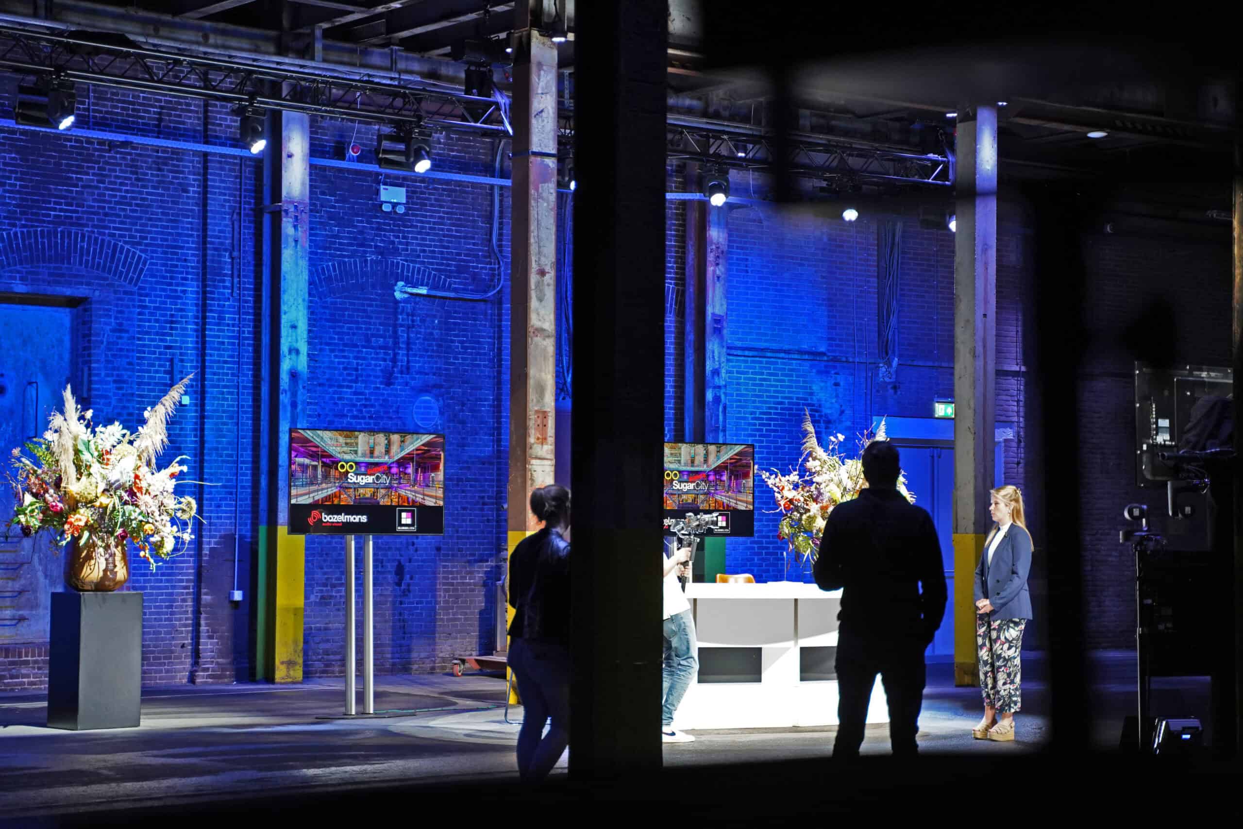 Moderne hybride evenementenlocatie met sfeervolle verlichting en digitale presentatiemogelijkheden.