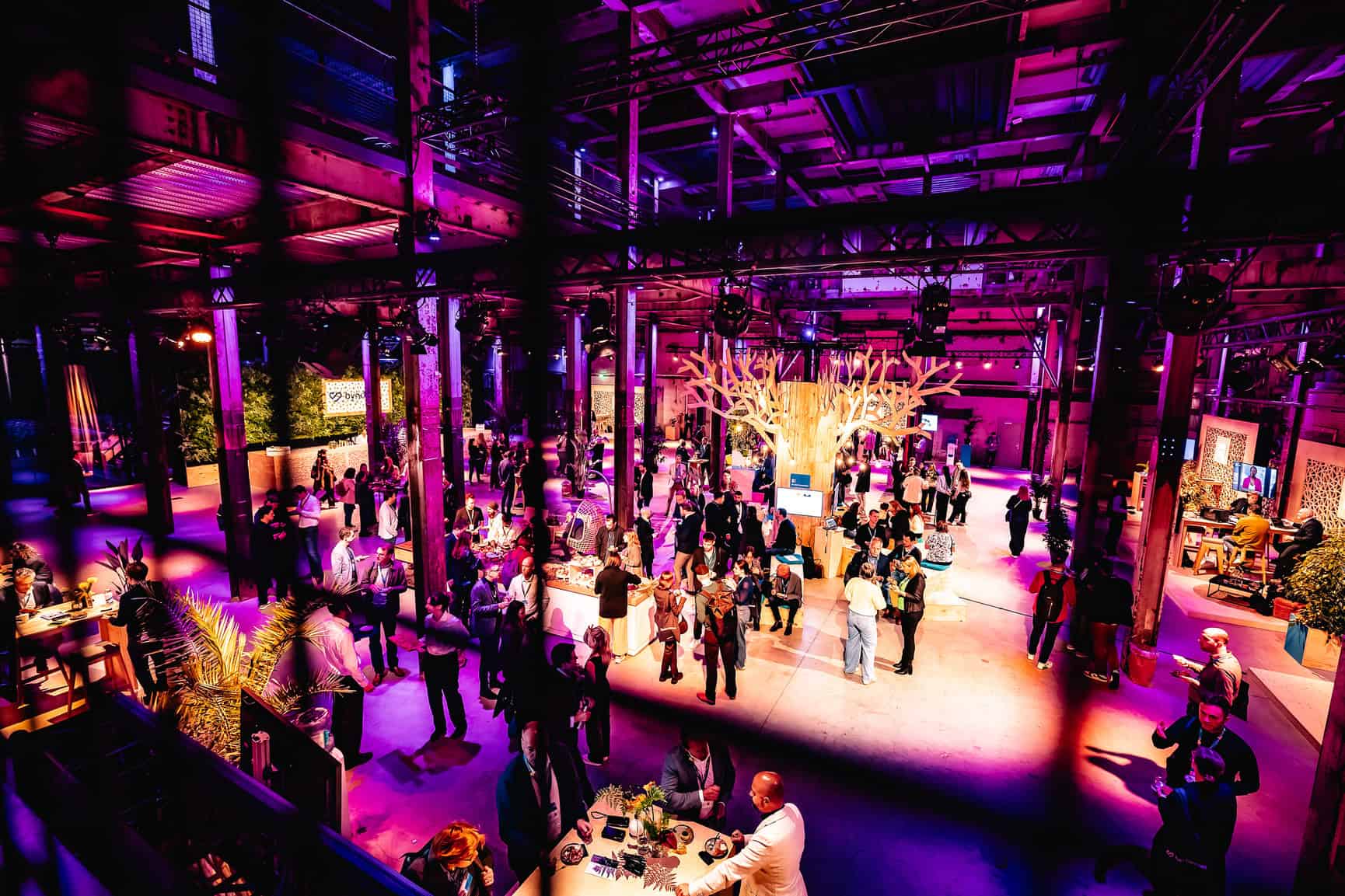 Bezoekers genieten van een evenement in de Middenfabriek bij SugarFactory, met kleurrijke verlichtin.