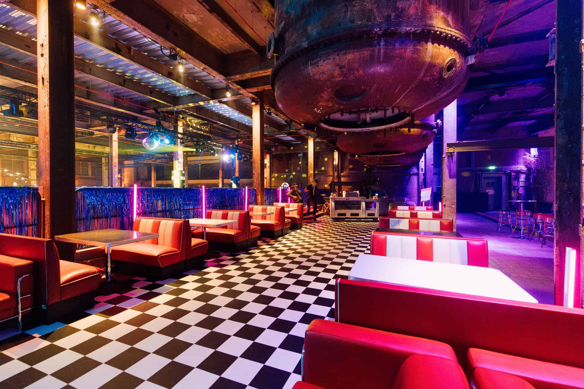 Industriële setting met kleurrijke verlichting en retro meubels in de Middenfabriek.