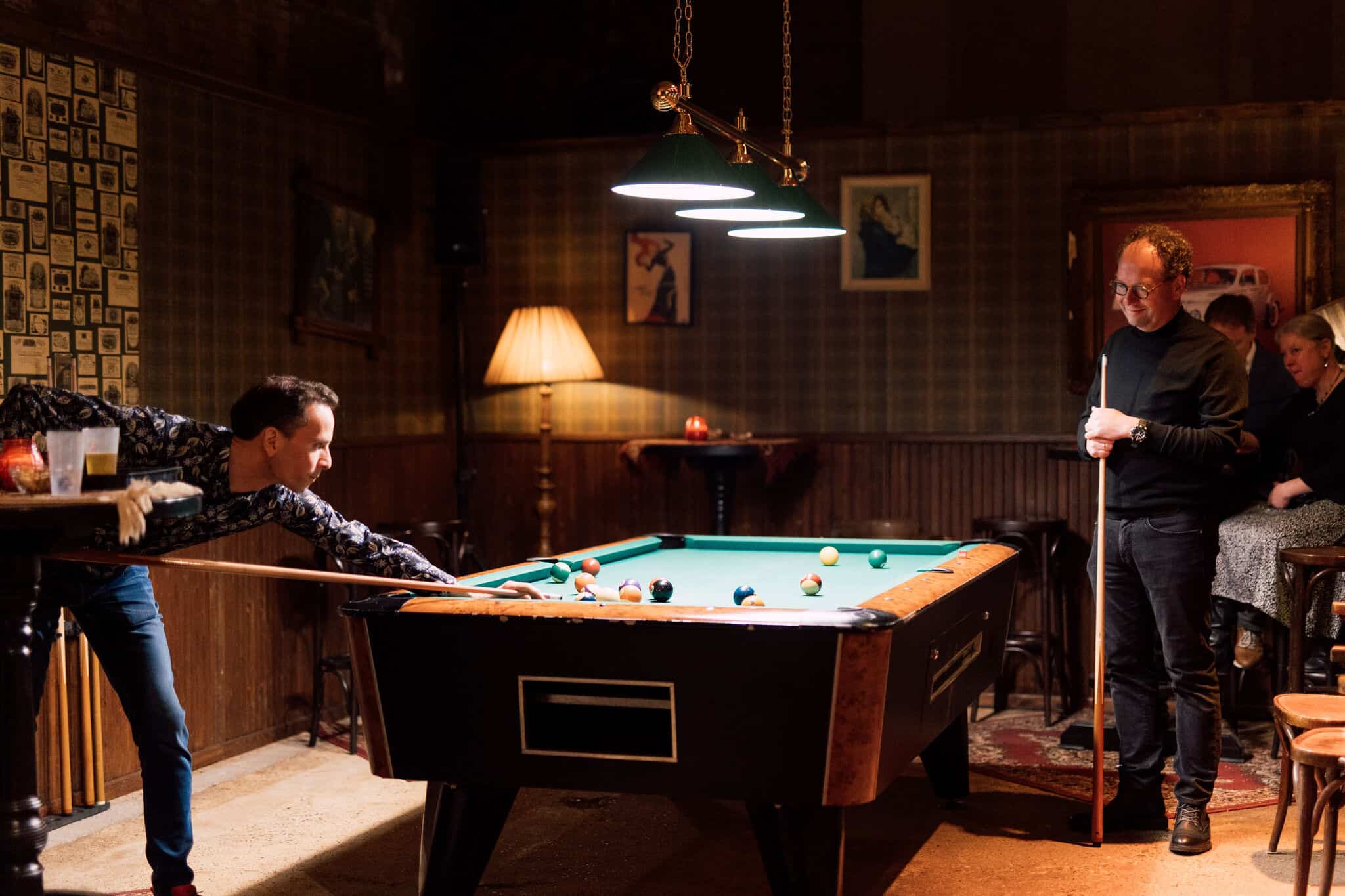 Biedenwasruimte met biljarttafel en mensen die spelen en genieten.