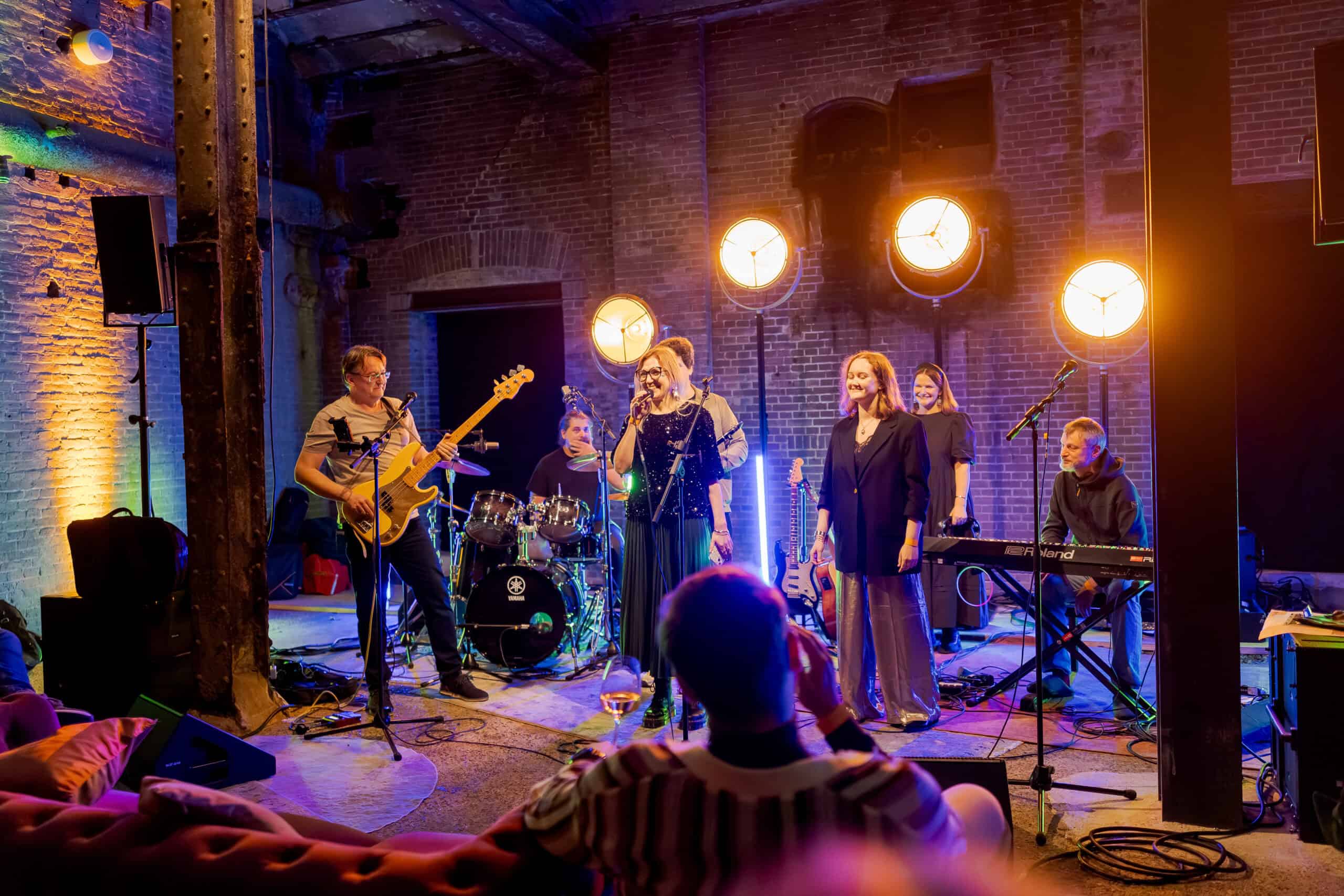 Live muziek optreden met zangeres en band in een industrieel interieur.