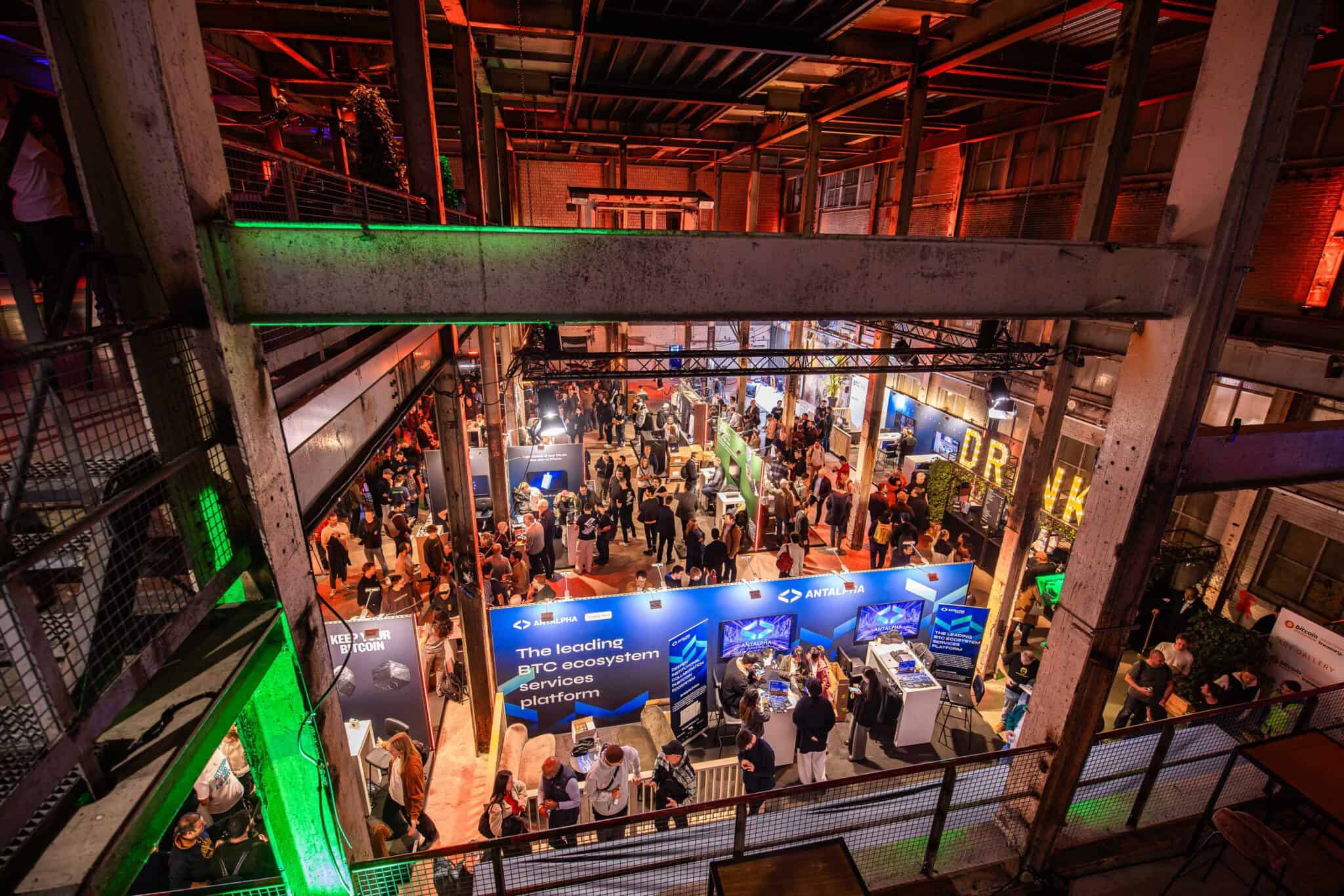 Beursvloer met bezoekers en stands in industriële setting.