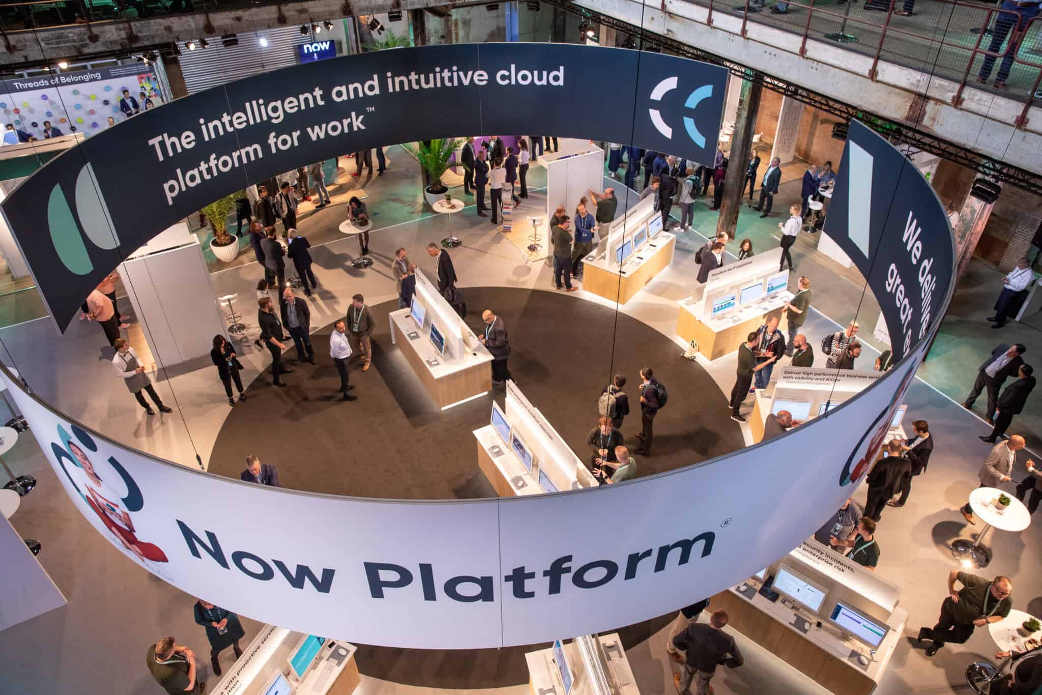 Beursvloer met technologie en bezoekers, grote ronde display met informatie over cloudplatforms.