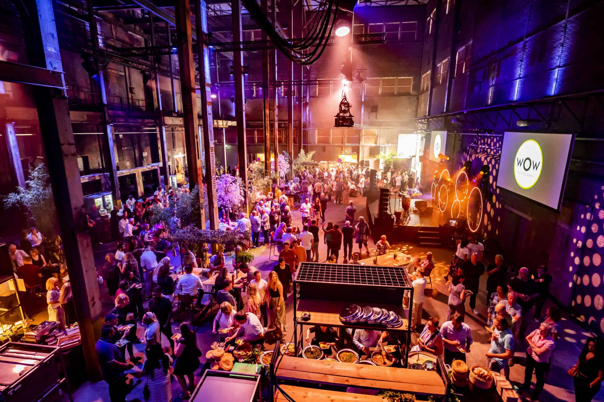 Personeelsfeest in een grote, kleurrijke feestzaal met dansvloer en DJ.