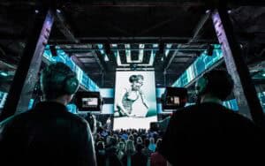 Bezoekers kijken naar een grote schermpresentatie tijdens een hackathon bij SugarFactory.