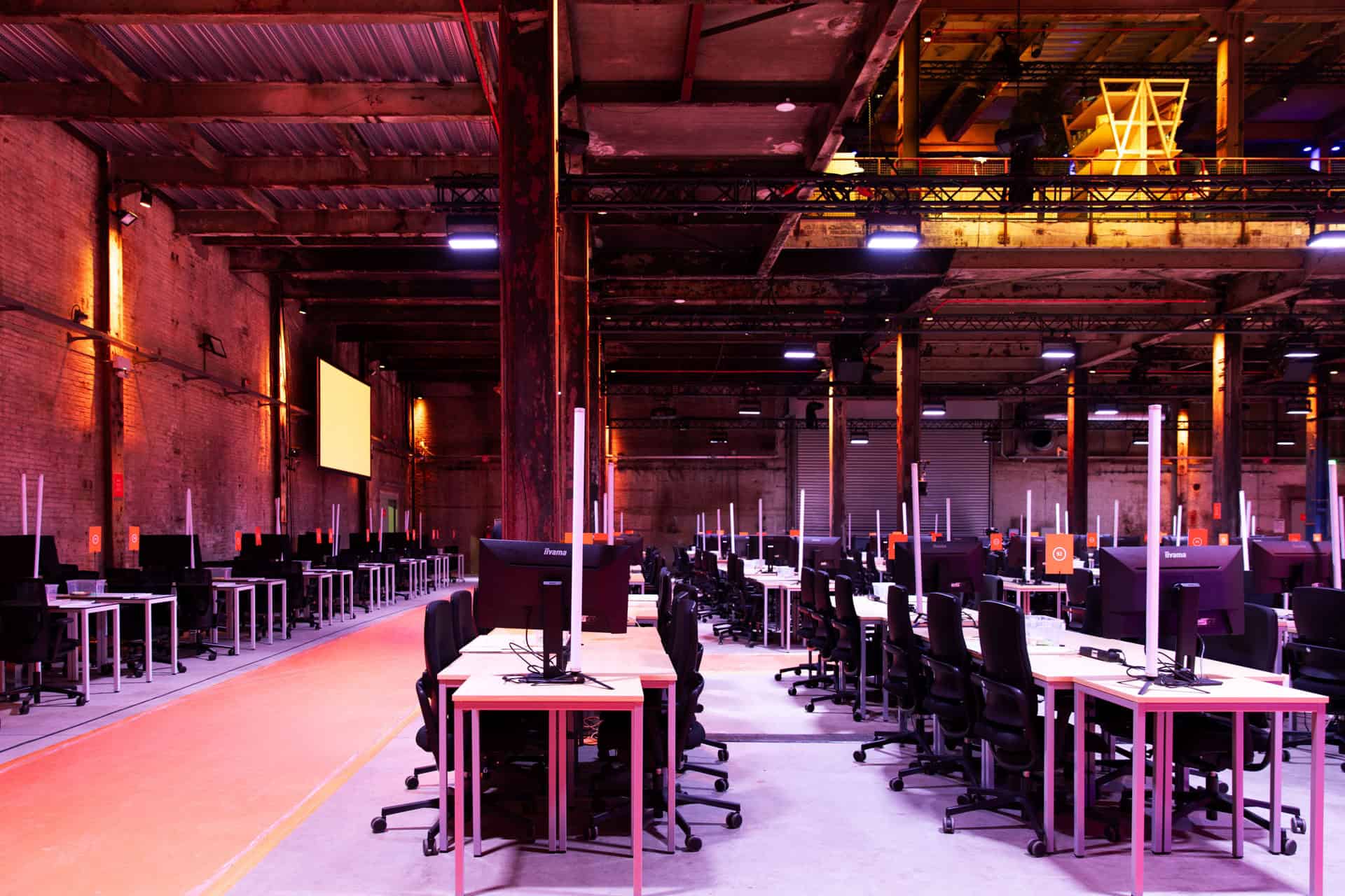 Hackathon werkruimte met computers en stoelen in industrieel pand.