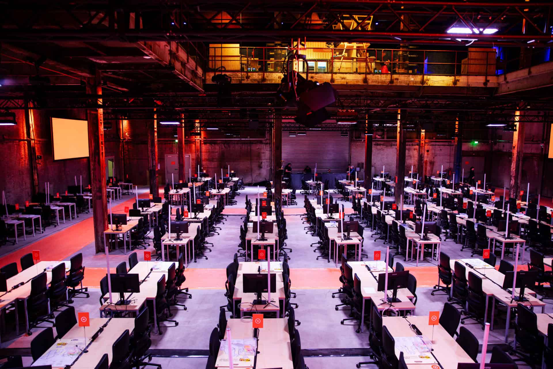 Grote hackathon gaming en werkruimte met meerdere werkstations en schermen.