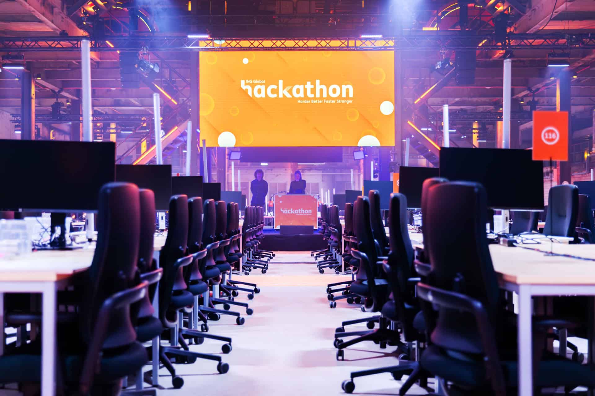 Hackathon zaal met lange tafels en comfortabele stoelen voor deelnemers.