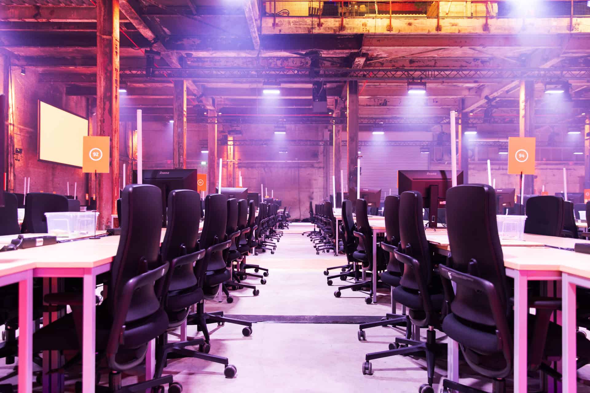 Hackathon werkruimte met rijen computers en comfortabele stoelen.