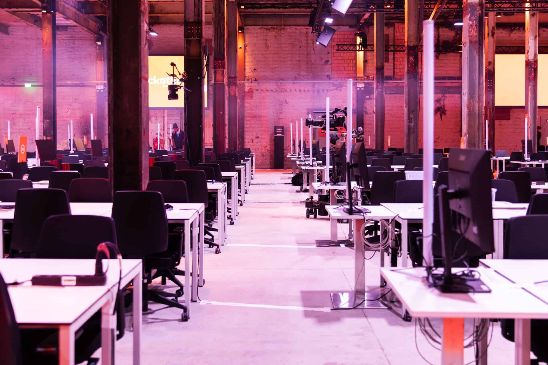 Moderne hackathon werkruimte met computers en stoelen in een industrieel gebouw.