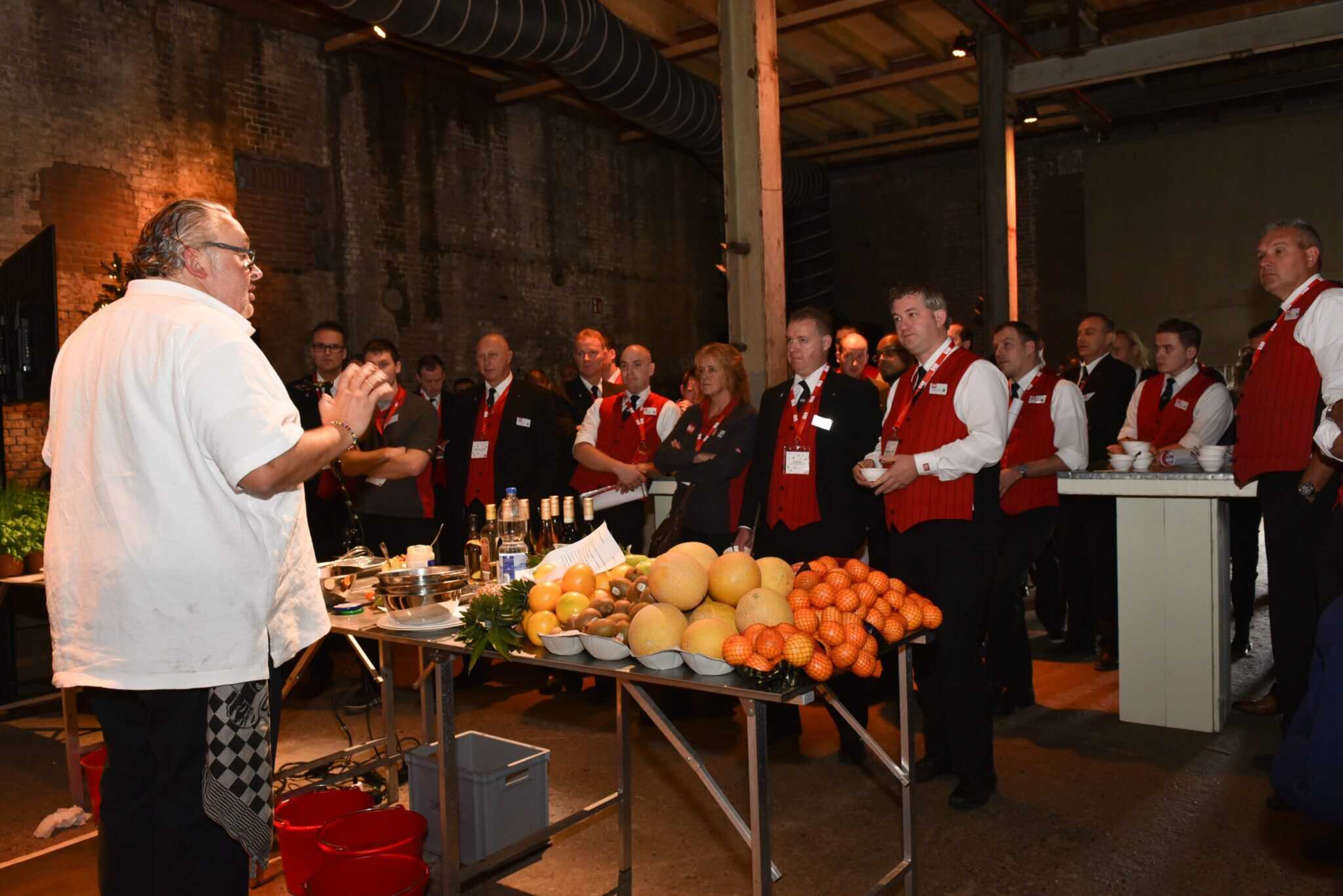 Chef geeft presentatie over feestdagen met vers fruit en hapjes.