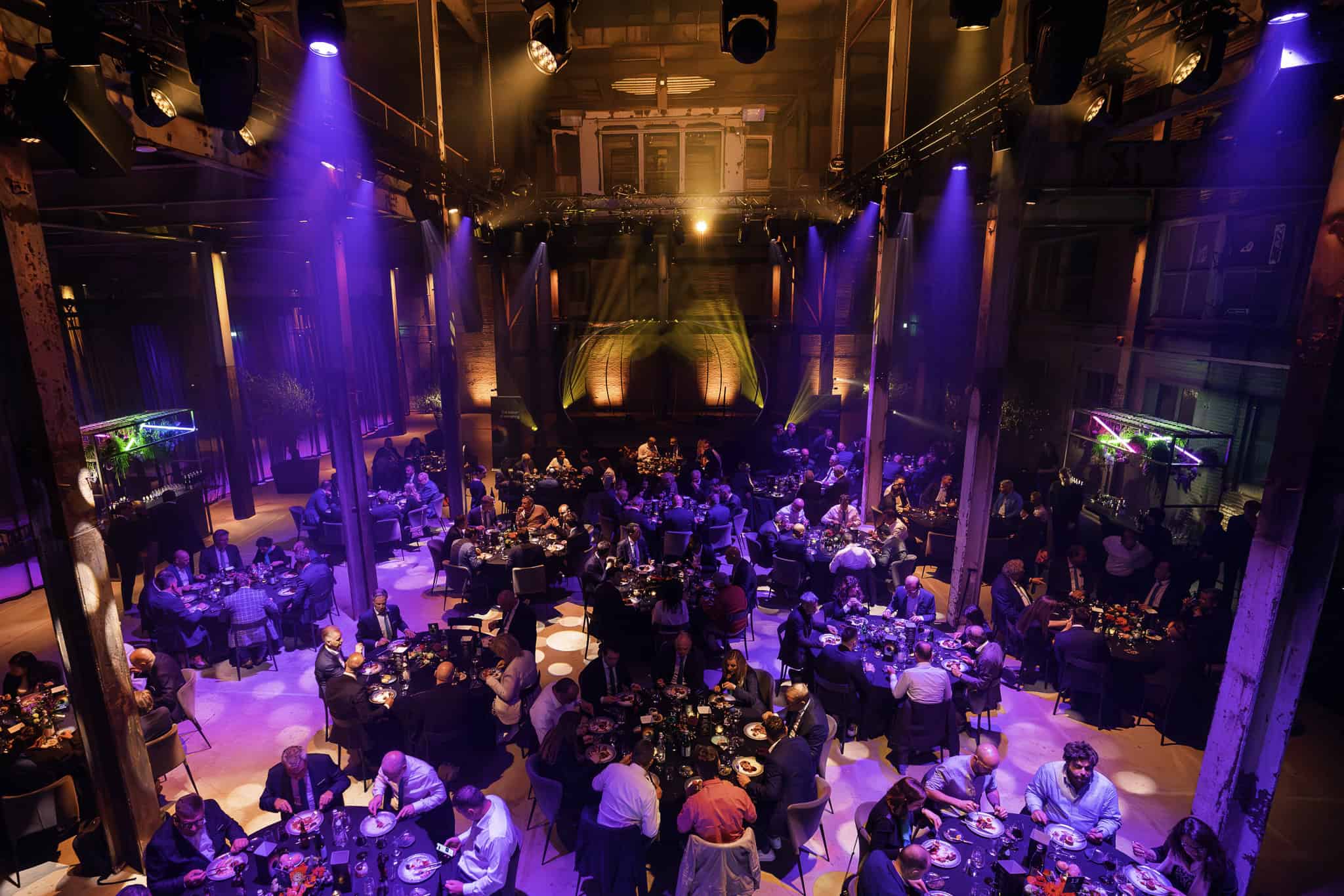 Axalta productlancering in een grote, sfeervolle zaal met veel gasten en kleurrijk licht.