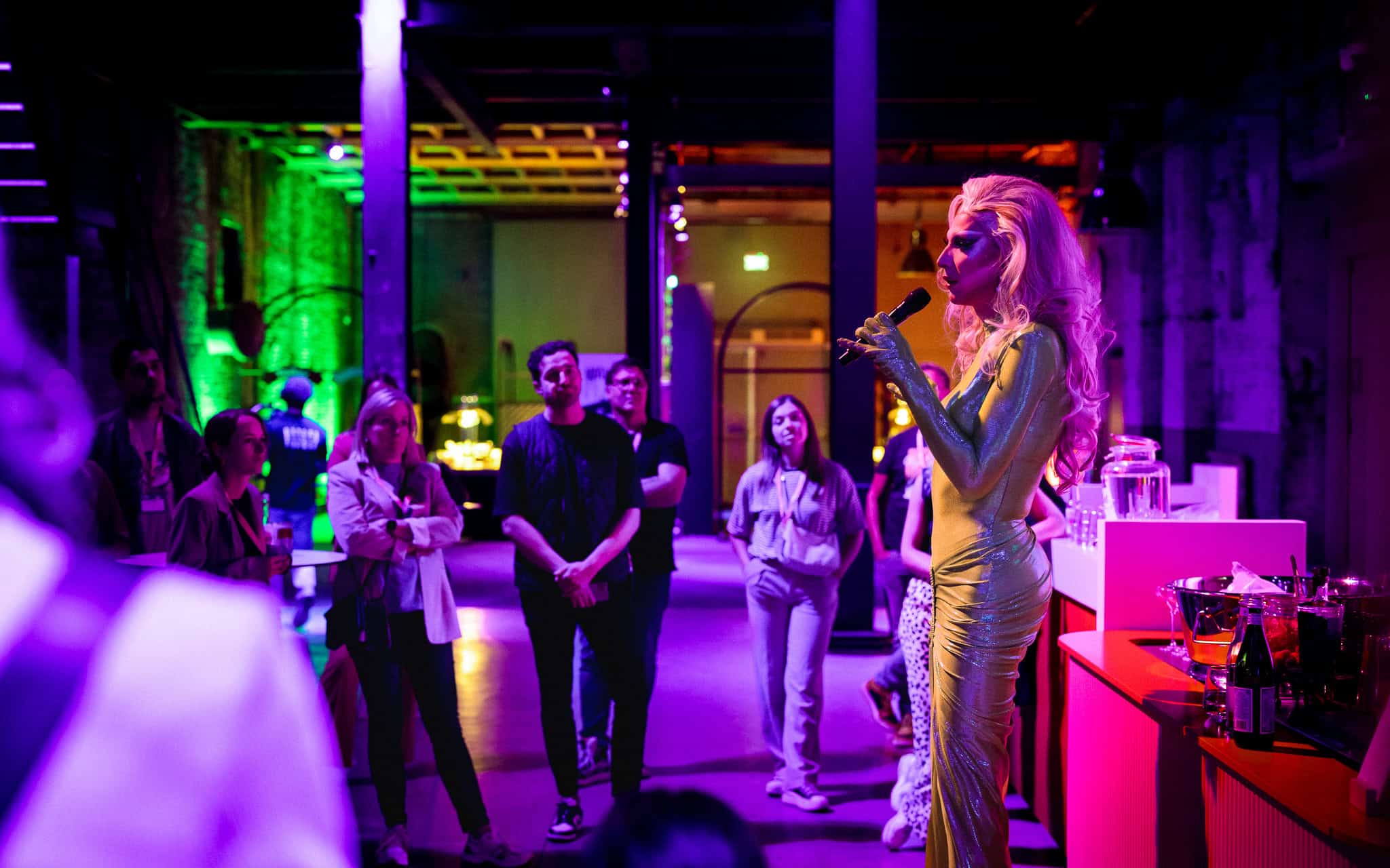 Een performer zingt tijdens een evenement met kleurrijk verlichte gasten.