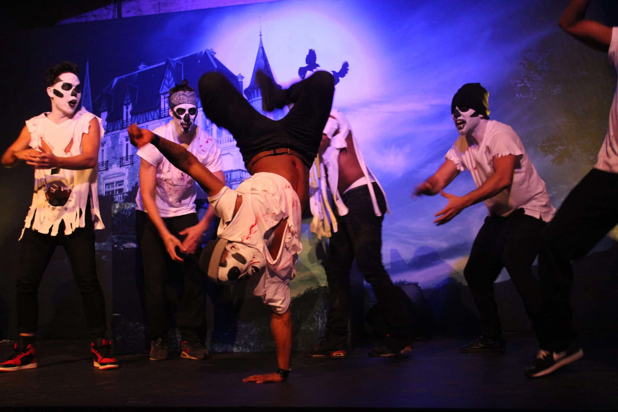 Mime performers in white costumes with face paint during a dance act.