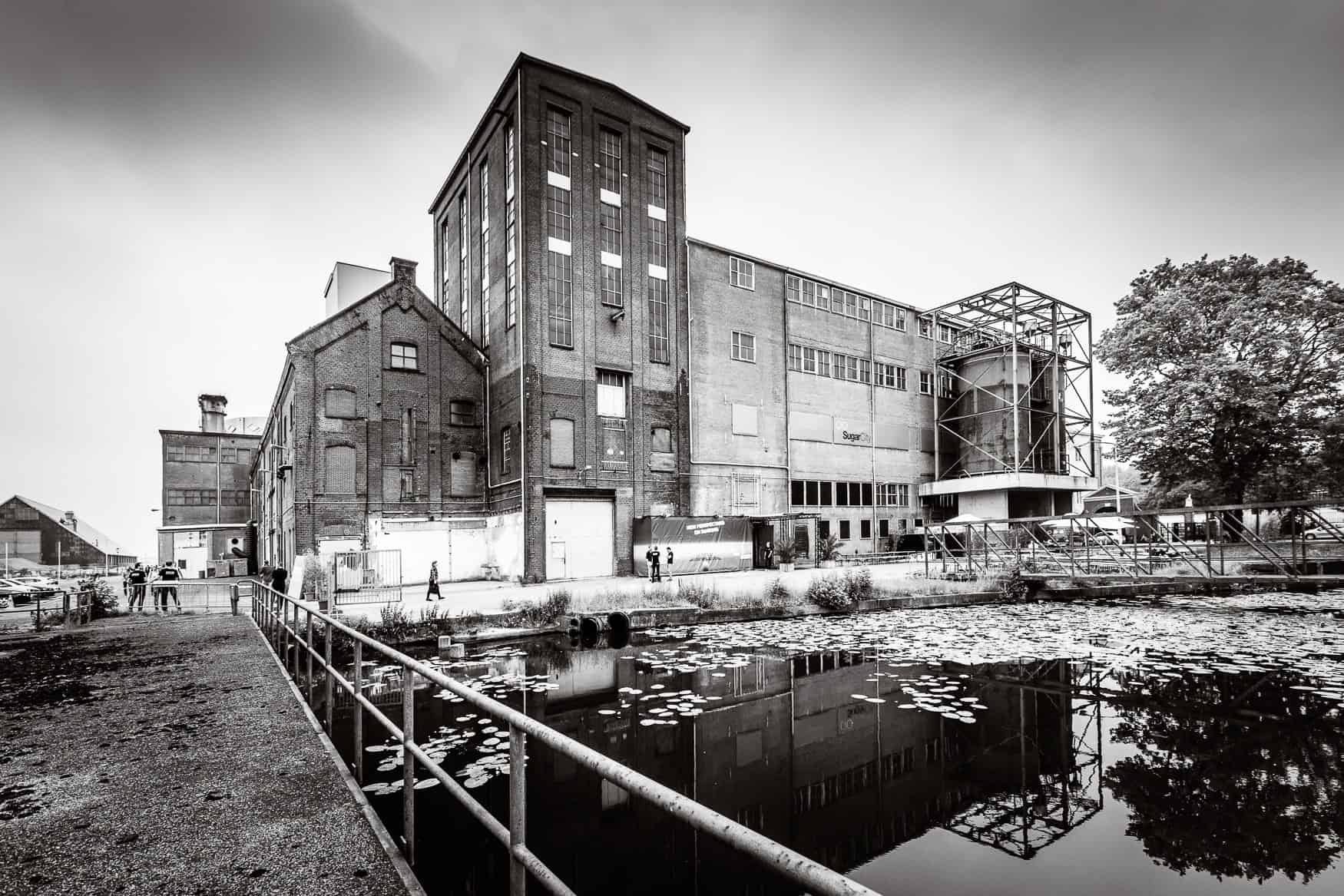 Modern industrieel gebouw bij SugarFactory met waterpartij en omringende natuur.