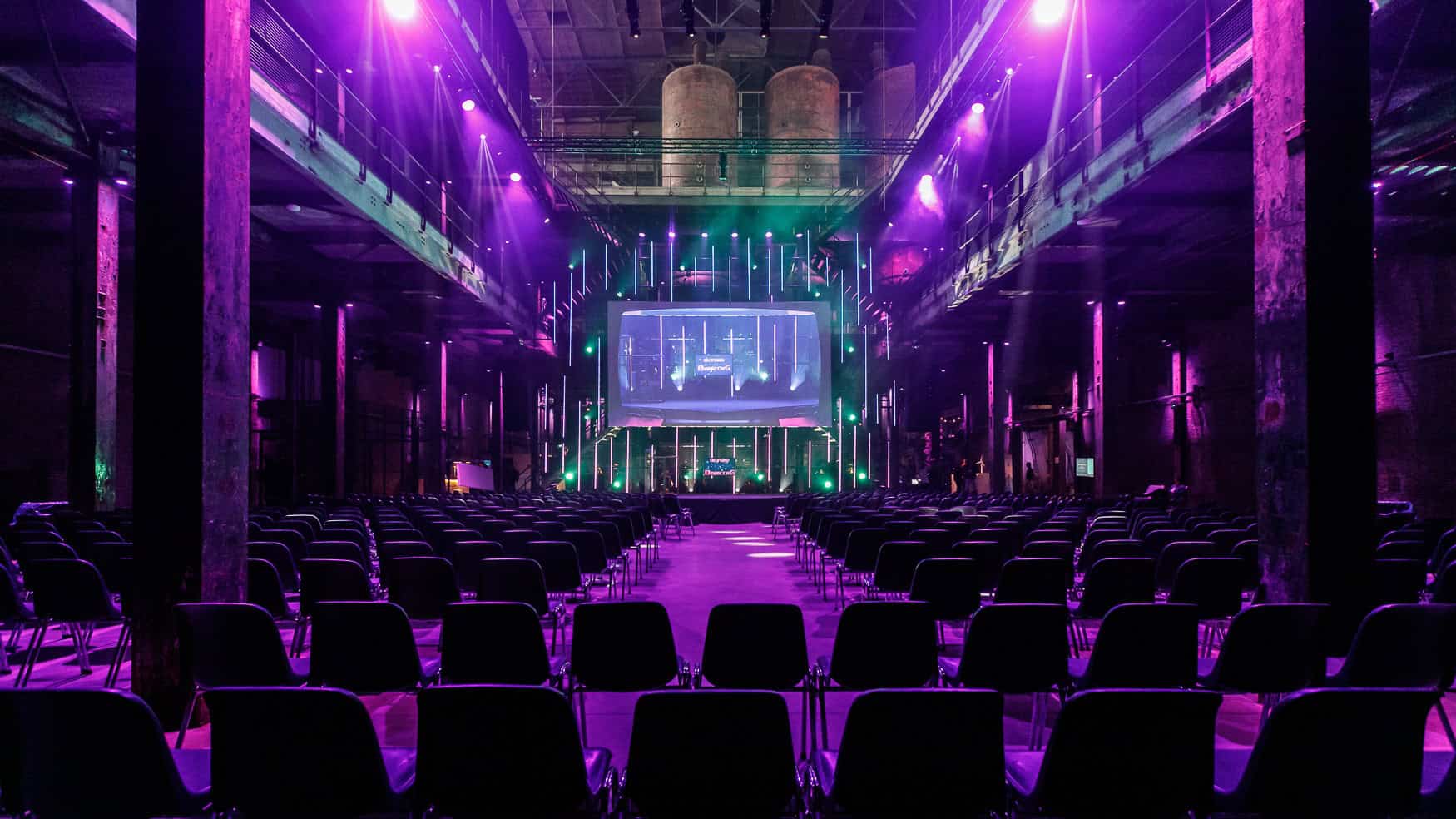 Innovatieve hackathon in de industriële setting van SugarFactory met kleurrijke verlichting.