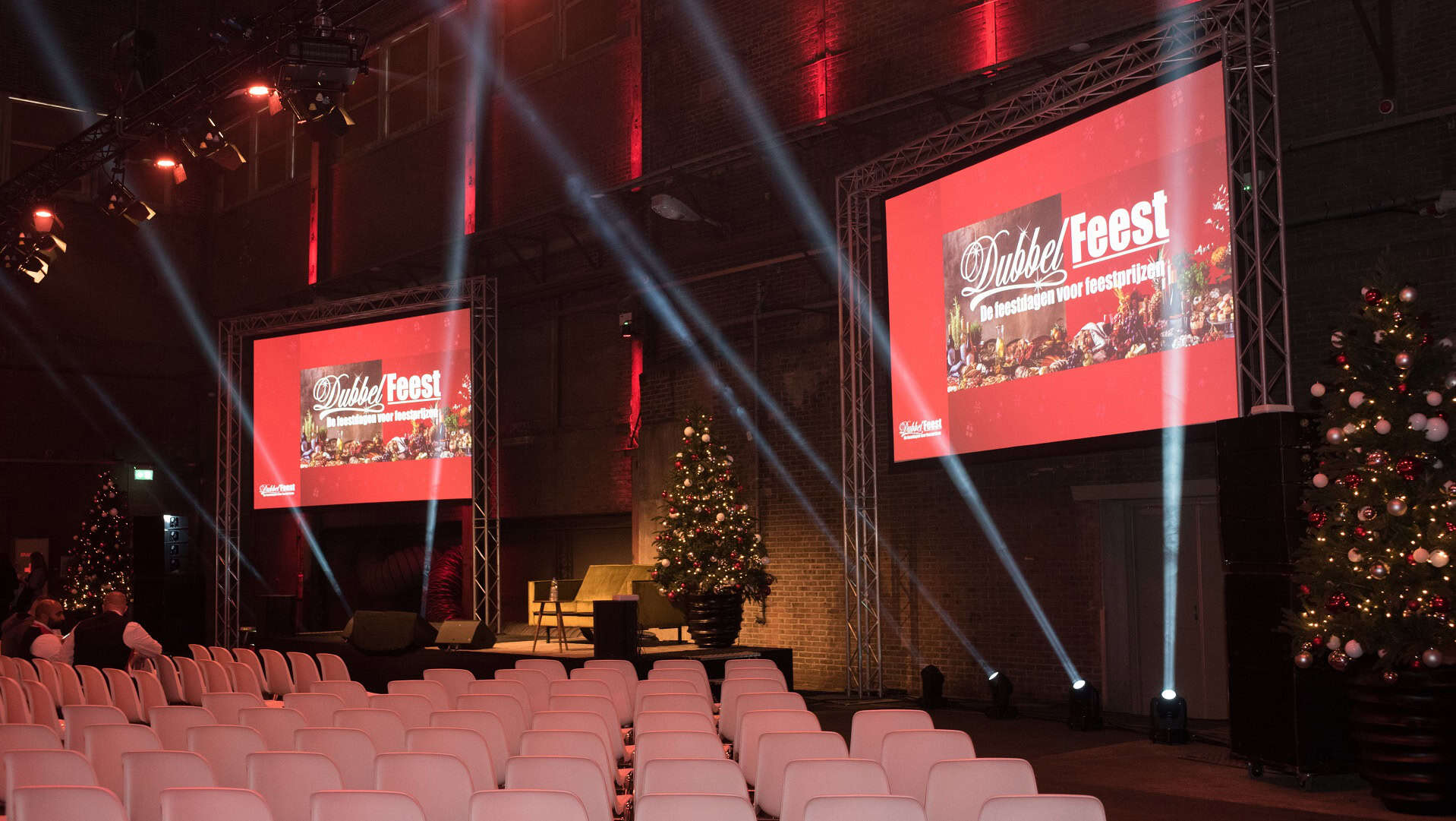 Feestzaal ingericht voor feestelijke presentatie met kerstversiering.