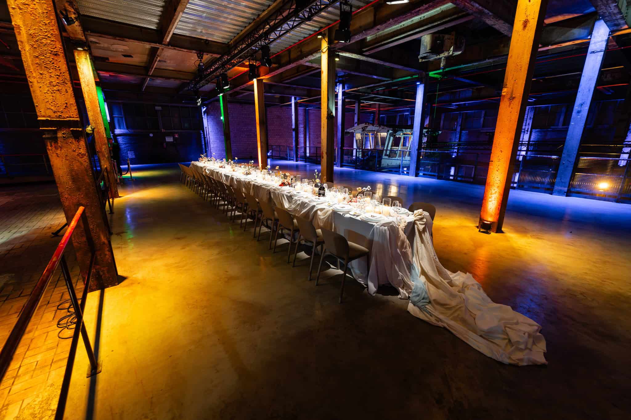 Een lange diner tafel in de industriële SugarFactory met kleurrijk verlichte omgeving.