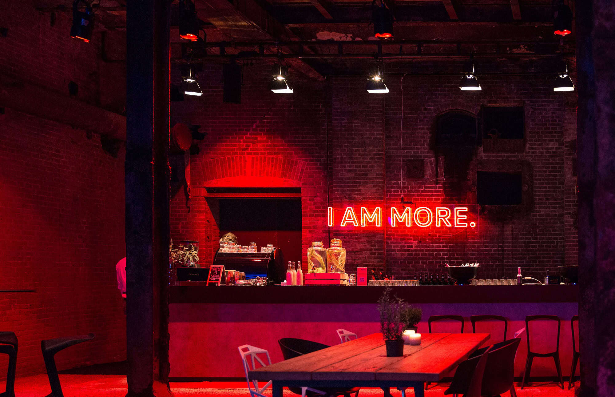 Neontekst "I AM MORE" in een industrieel interieur van SugarFactory, perfect voor een avond uit.