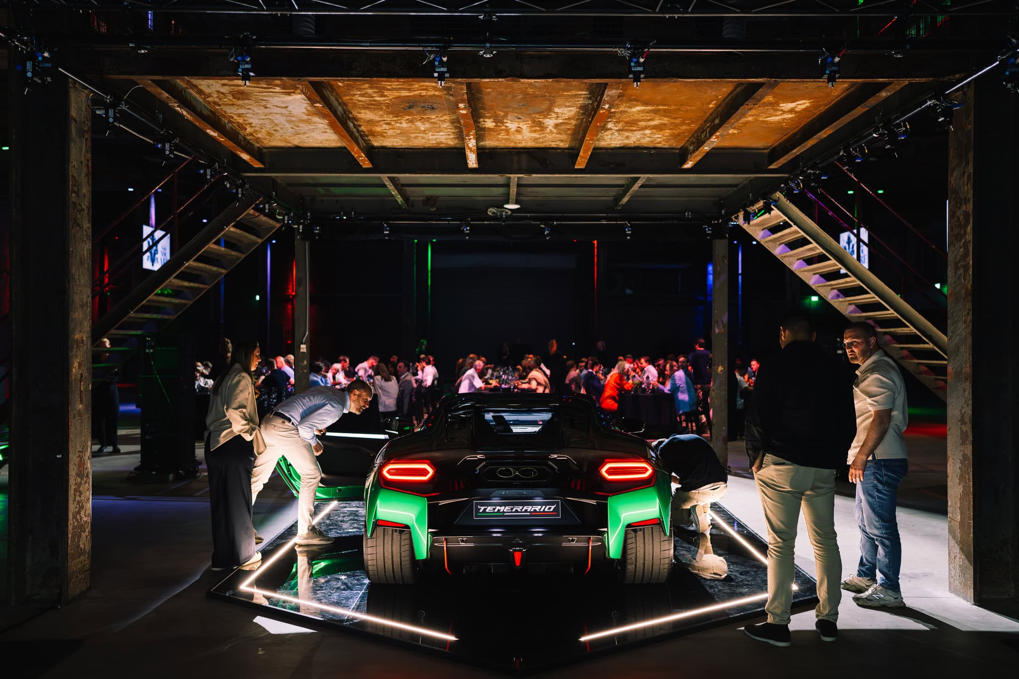 Luxe sportauto tijdens productpresentatie in moderne showroom met bezoekers en verlichting.