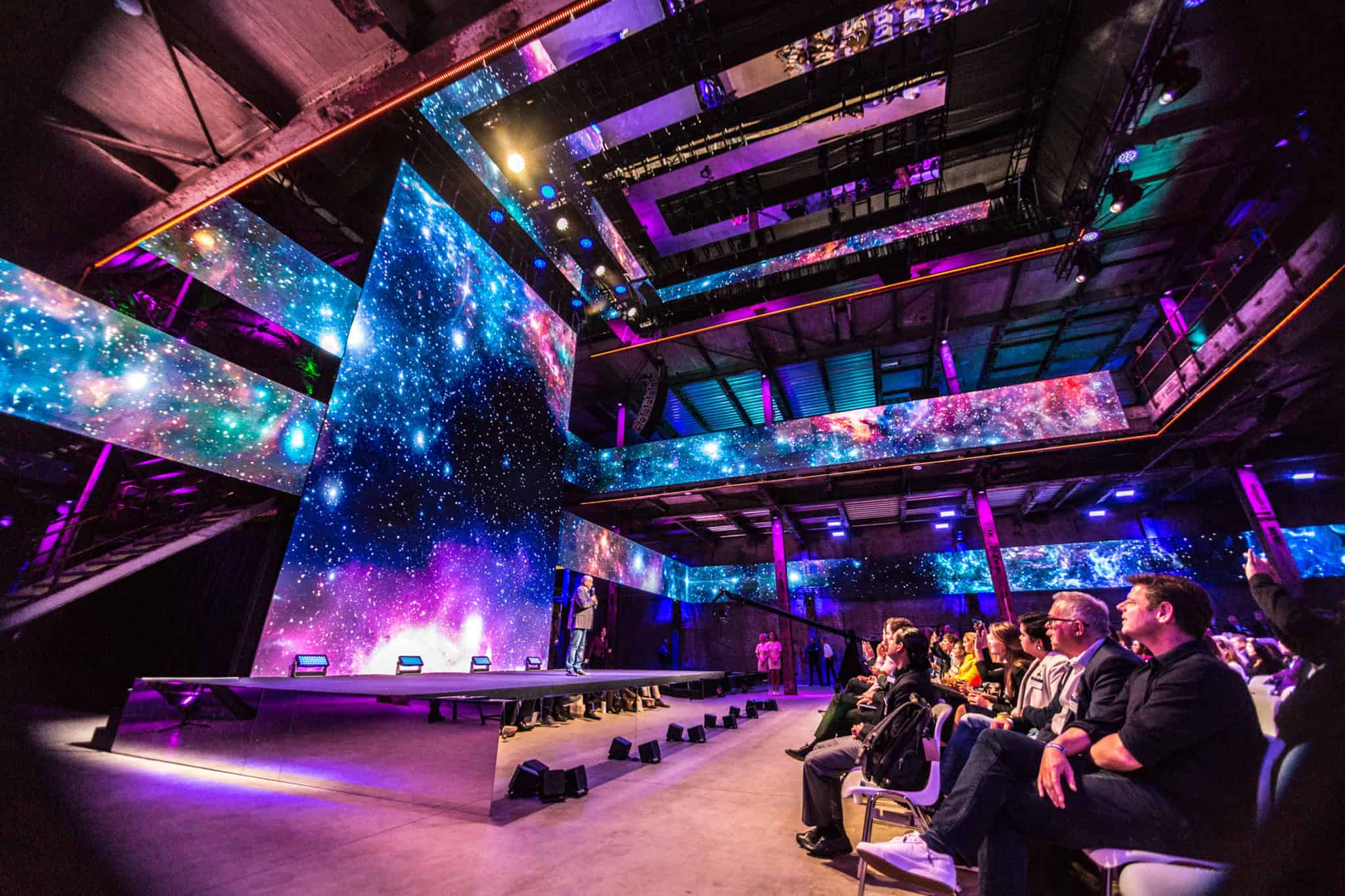 Moderne congresruimte met grote LED-schermen en kleurrijk lichtontwerp.