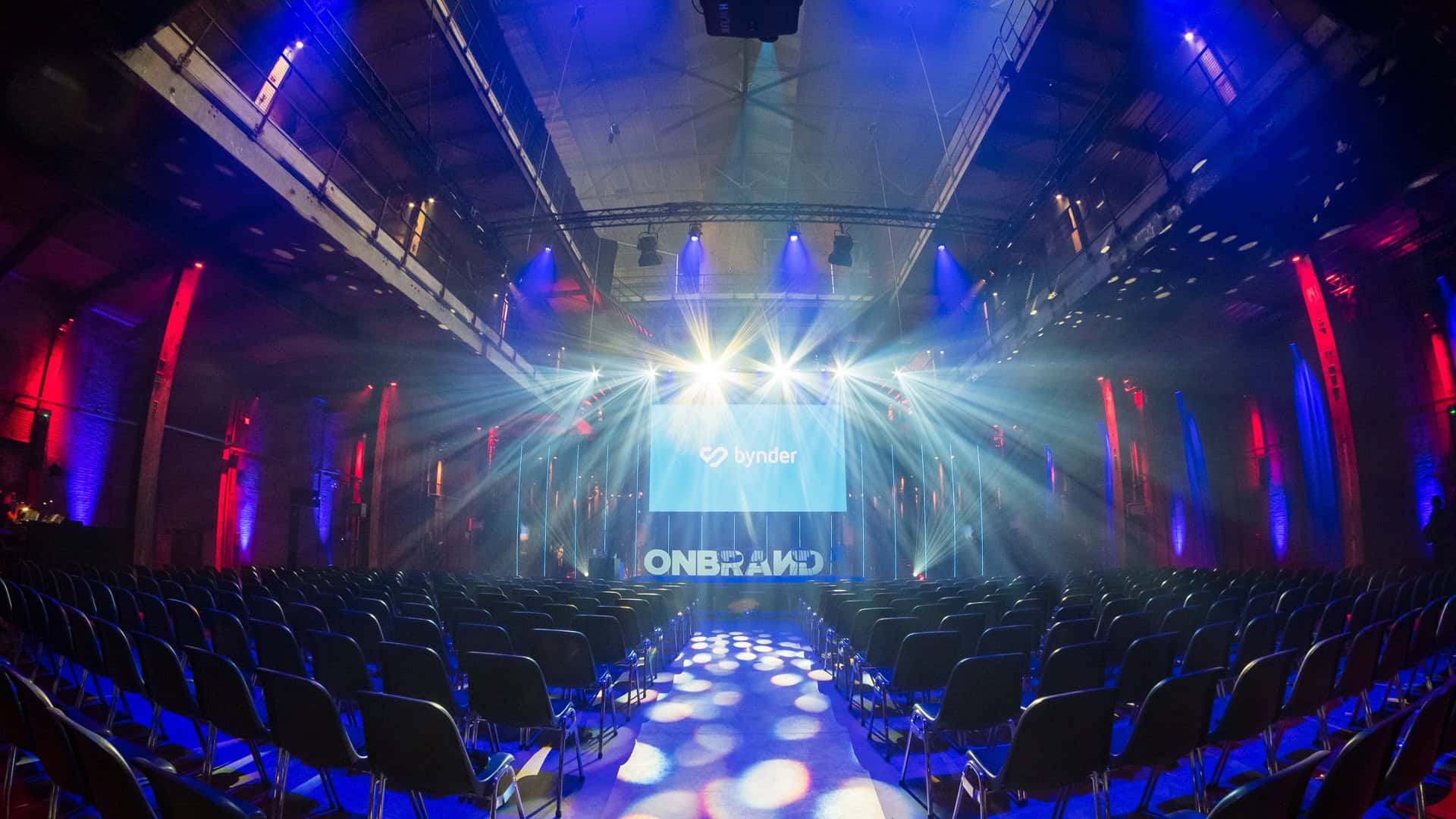Evenementenlocatie bij SugarFactory met podium en kleurrijke verlichting.