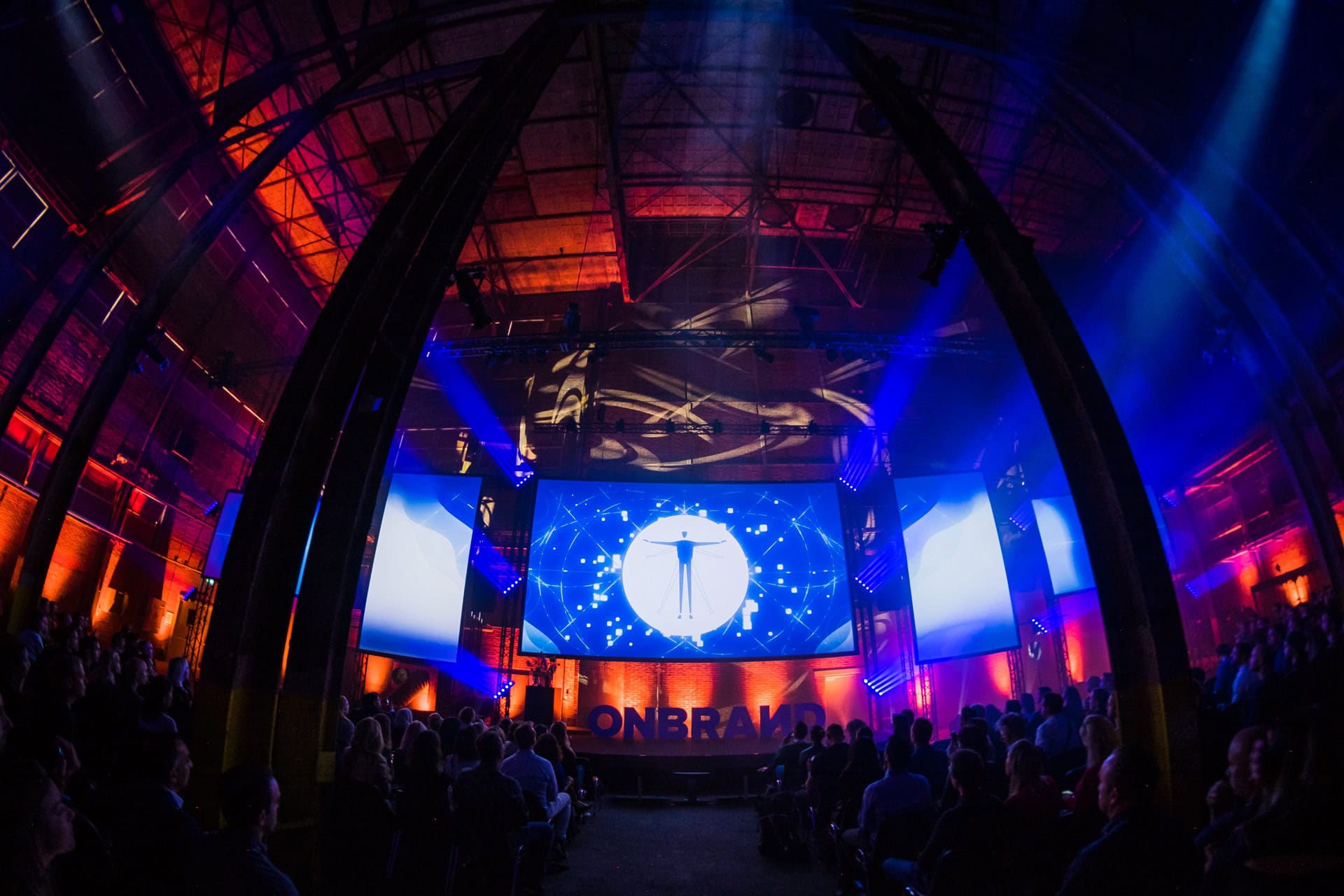 Evenementlocatie met grote schermen en kleurrijk licht.
