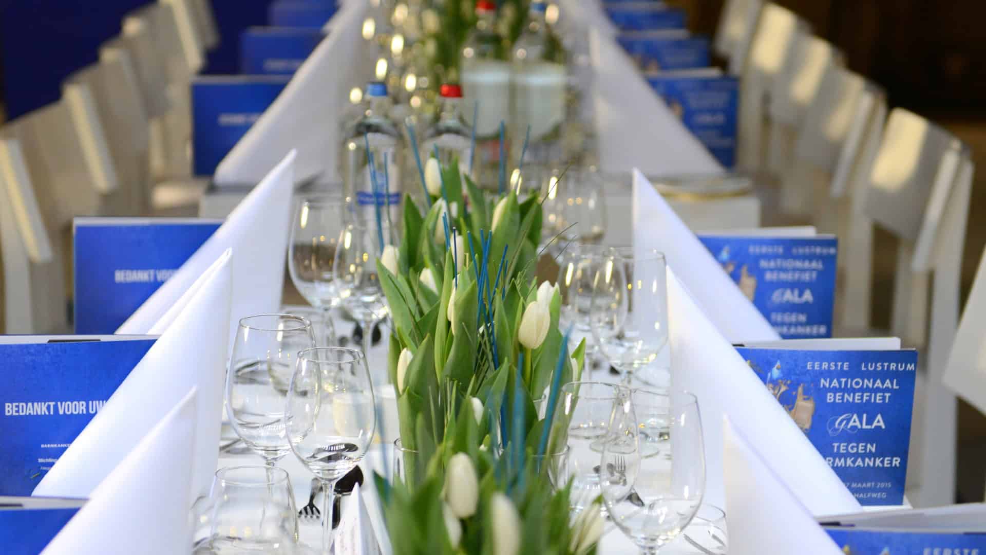 Tafel gedekt voor evenement met tulpen en informatie over darmkanker in Nederland.