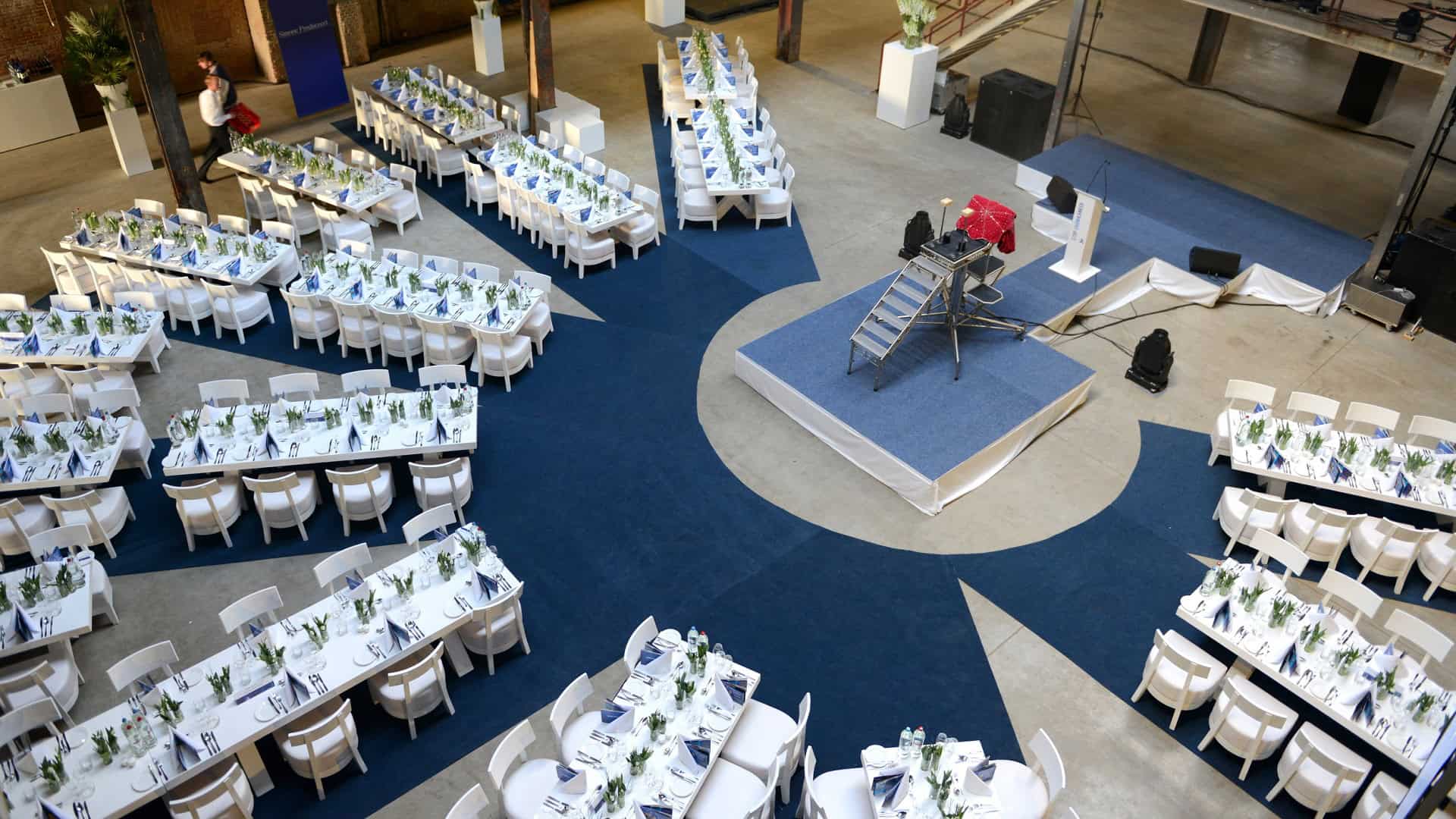 Grote zaal met ronde tafels en podium tijdens SugarFactory evenement 2015.