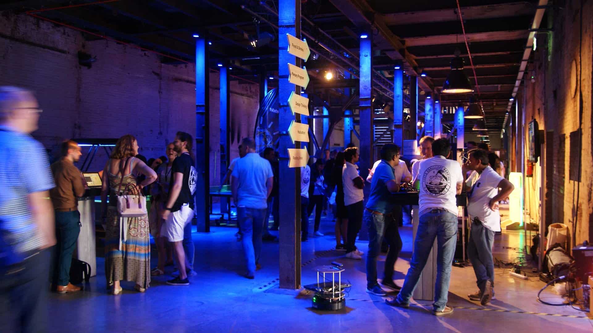 Mensen netwerken bij SugarFactory tijdens 'Beyond Banking' evenement in een industrieel interieur.