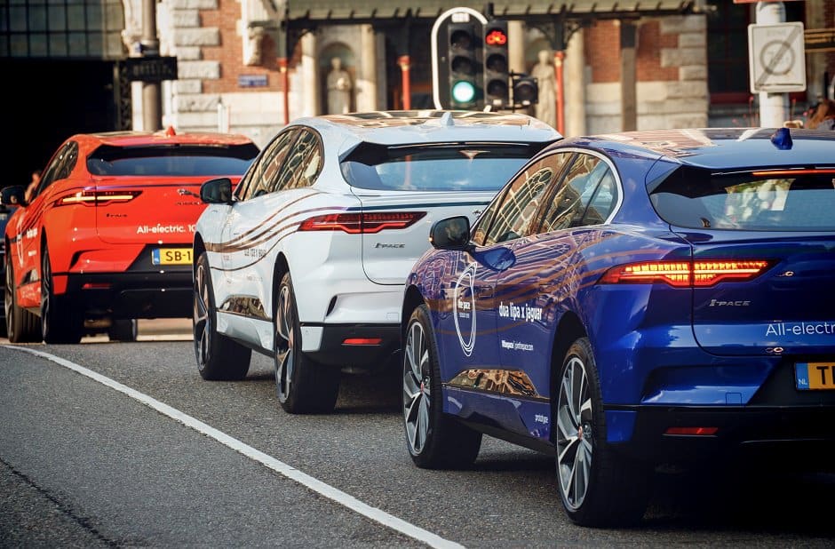 Drie elektrische auto's wachten bij het verkeerslicht in een stad.