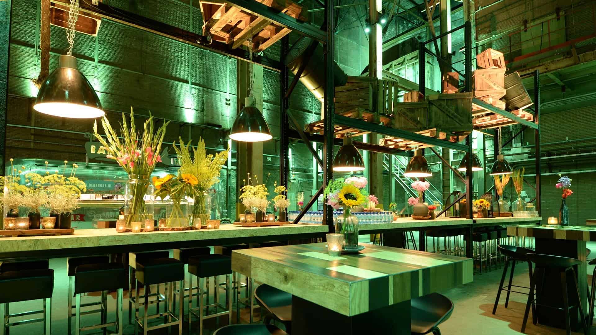 Interieur van de SugarFactory met bloemen en groene verlichting.