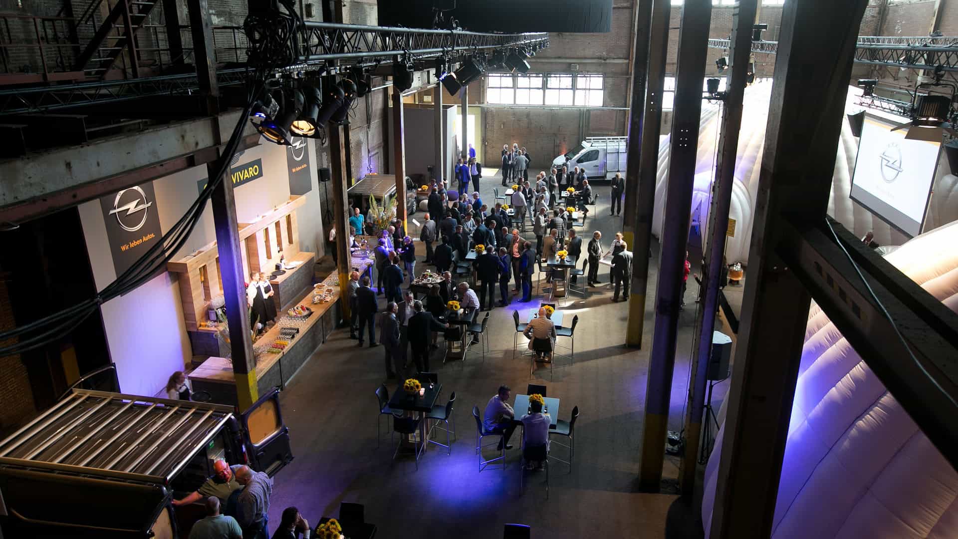 Opel auto op show in industriële locatie met bezoekers en displays.