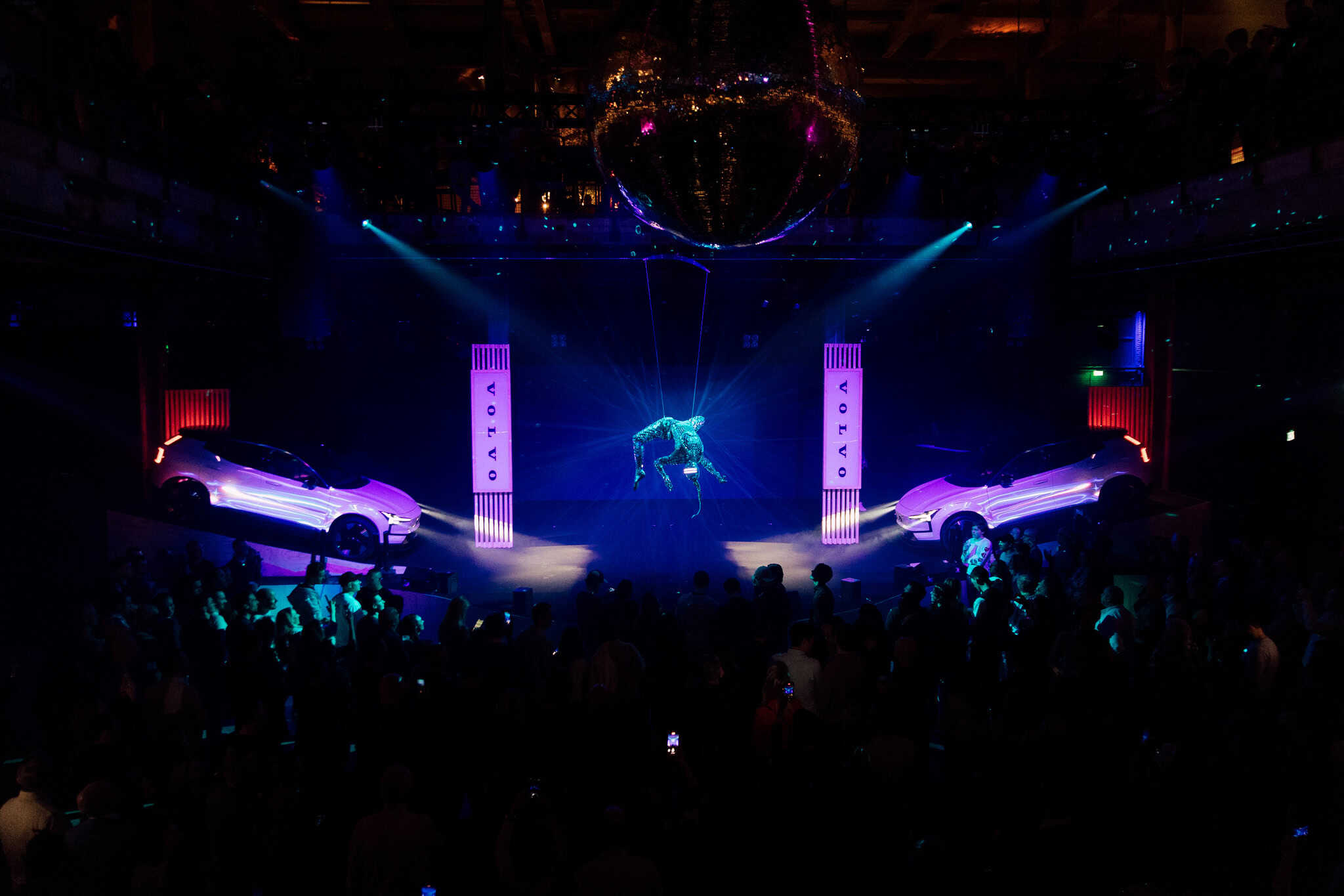 Luxe auto’s en verlichte show tijdens productpresentatie in evenementenzaal.