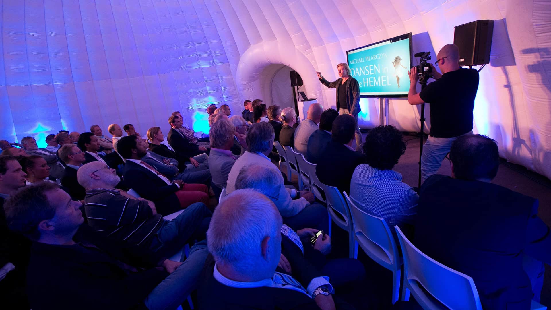 Spreker presenteert Opel aan een publiek in een moderne setting.